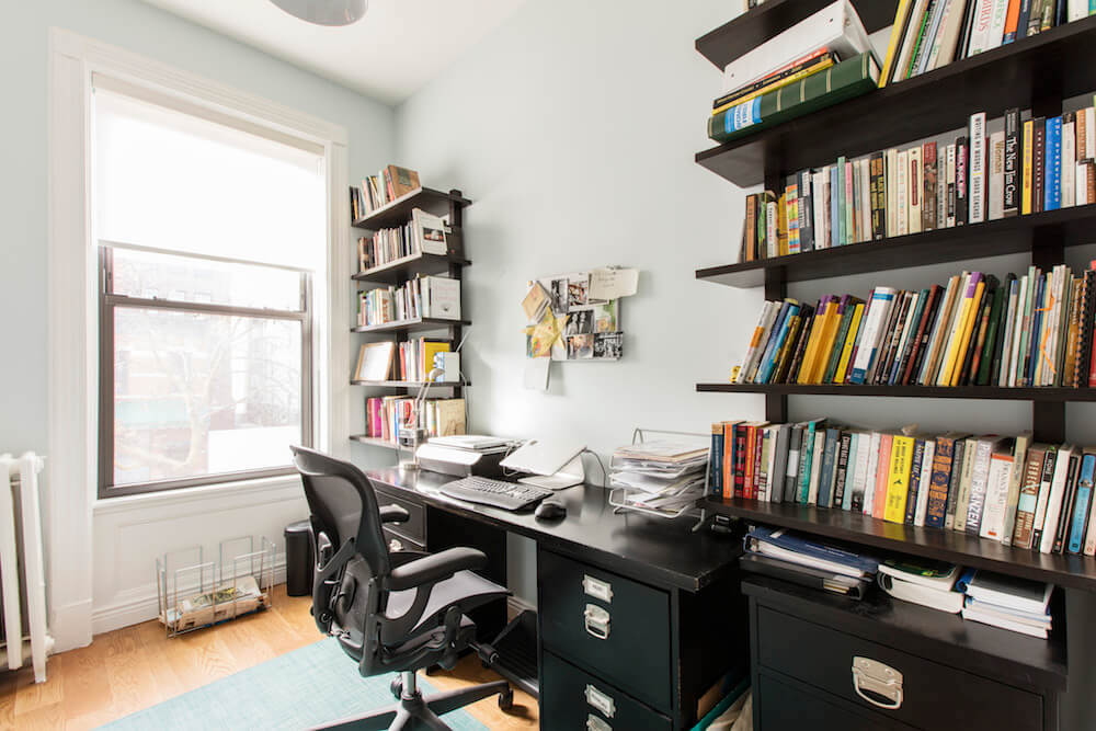 Office with black desk, book shelves, and large window