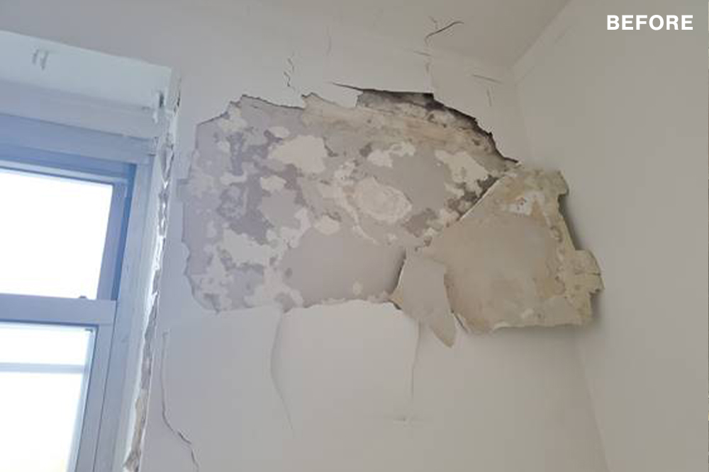 A wall with cracked paint and plaster before renovations