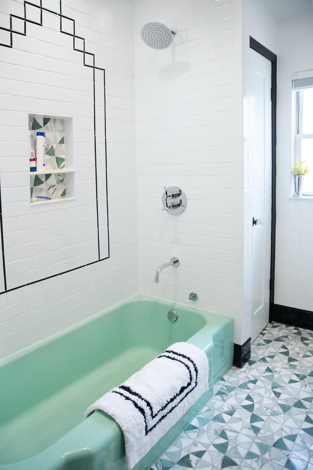 White tiled bathroom with green tub and patterned tiling