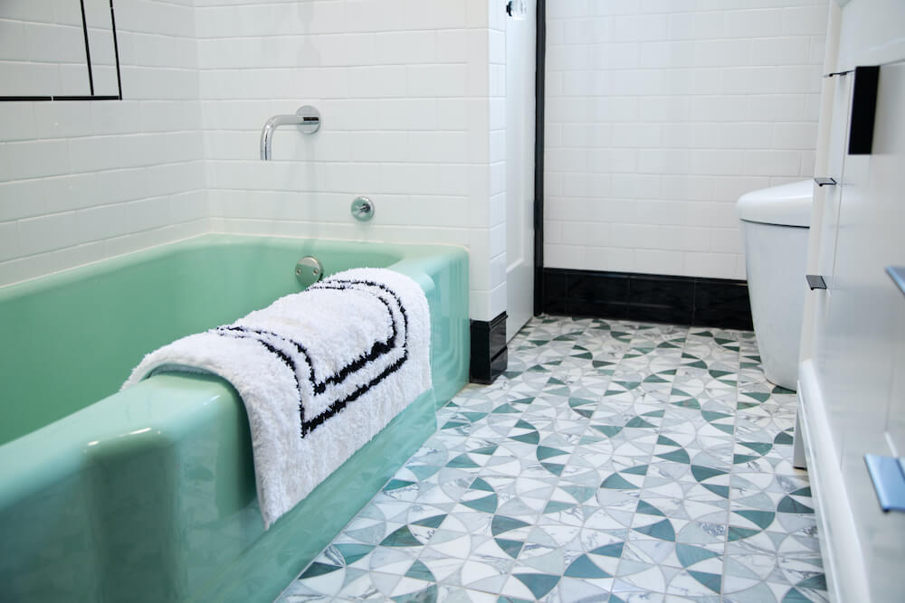 Seafoam green bathtub with art deco floor tiles