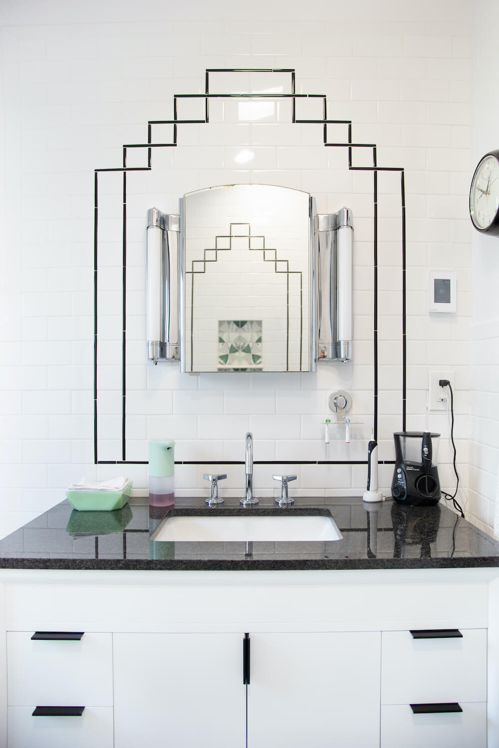 Bathroom sink vanity framed by stylized tile patterning