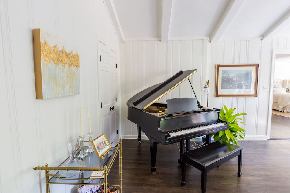 The grand piano in the renovated den with a large plant
