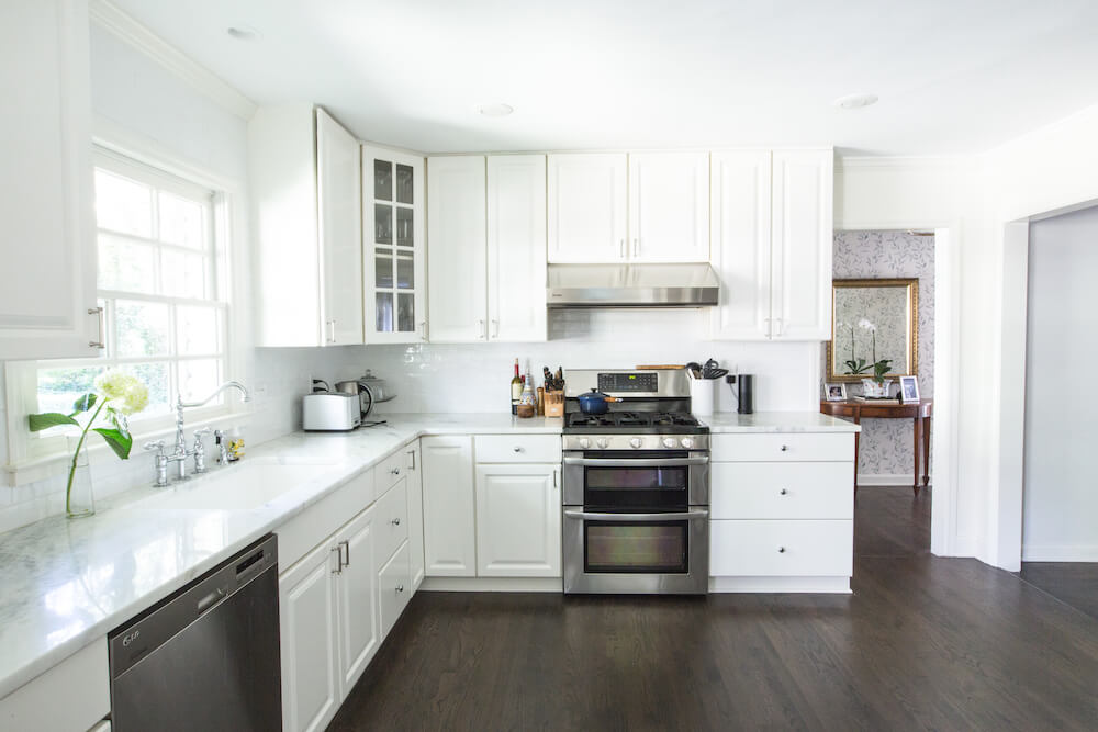 White marble counters, white cabinets and dark hardwood floors in the kitchen