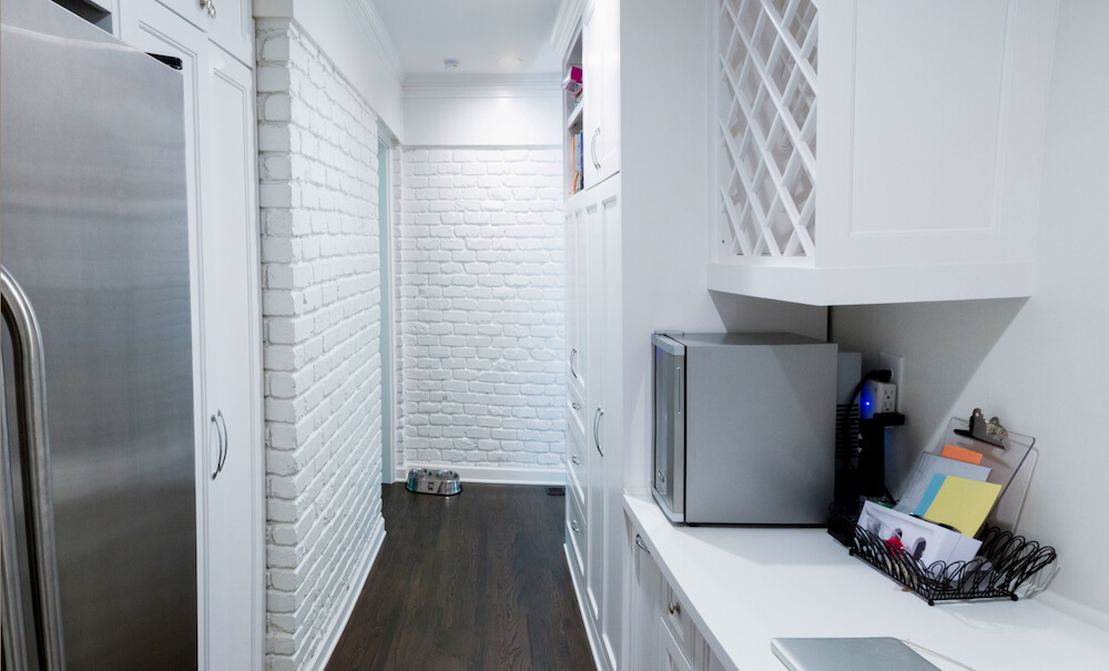 The back hallway with white cabinets and extra fridge