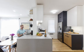A man sitting on his kitchen peninsula looking at his laptop