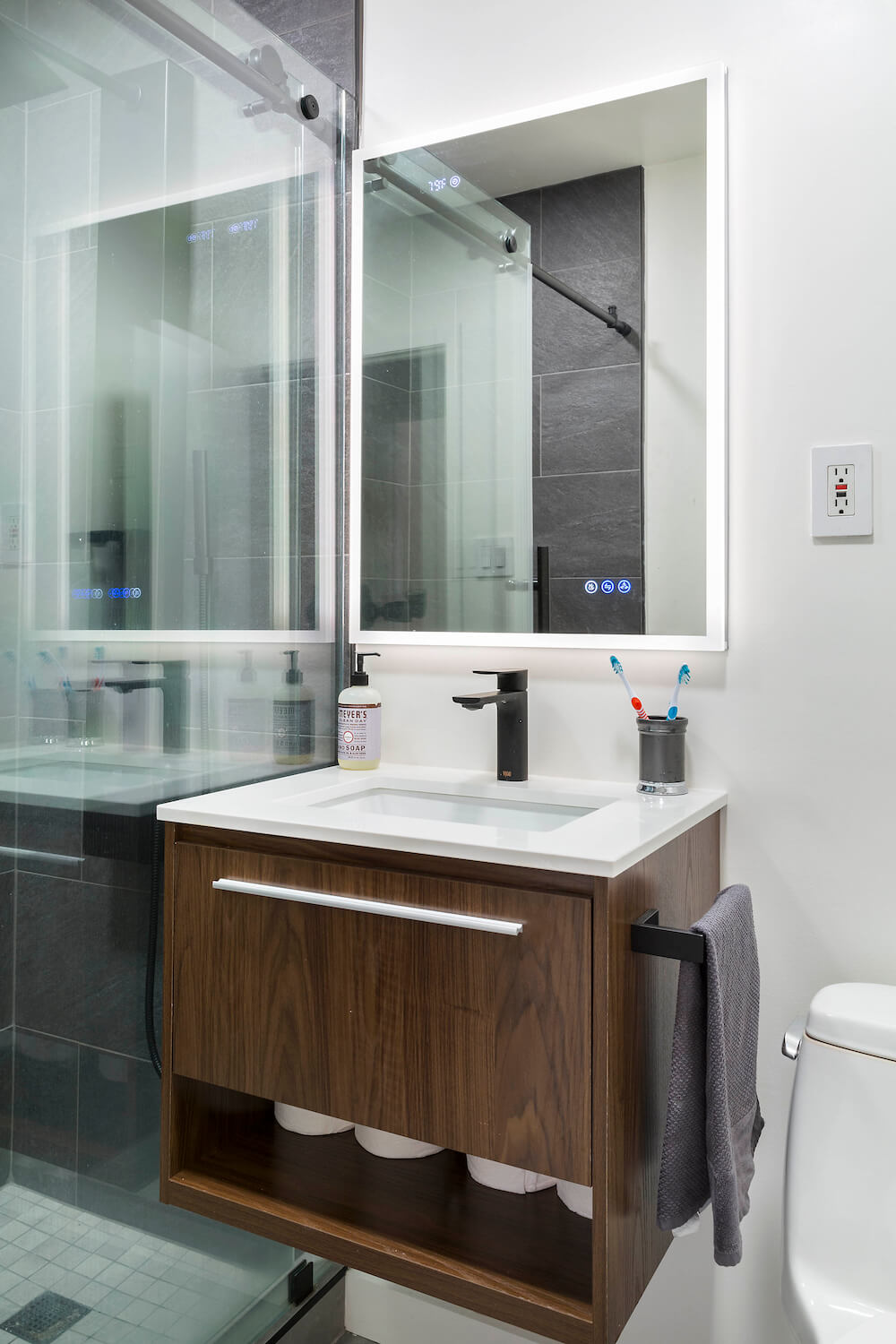 Dark wood floating bathroom vanity with toilet paper storage