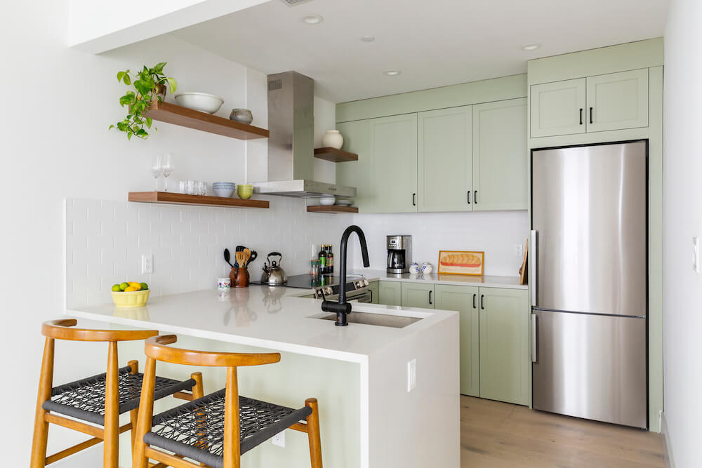 Kitchen with bottom freezer refrigerator and mint green cabinets