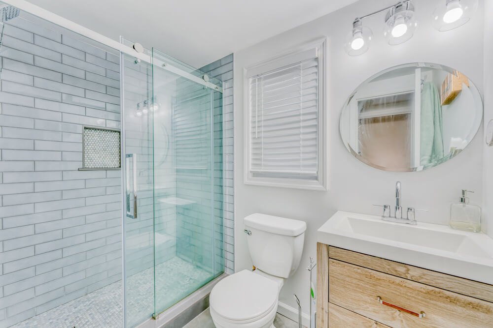 Bathroom with wood vanity, light blue shower and white walls