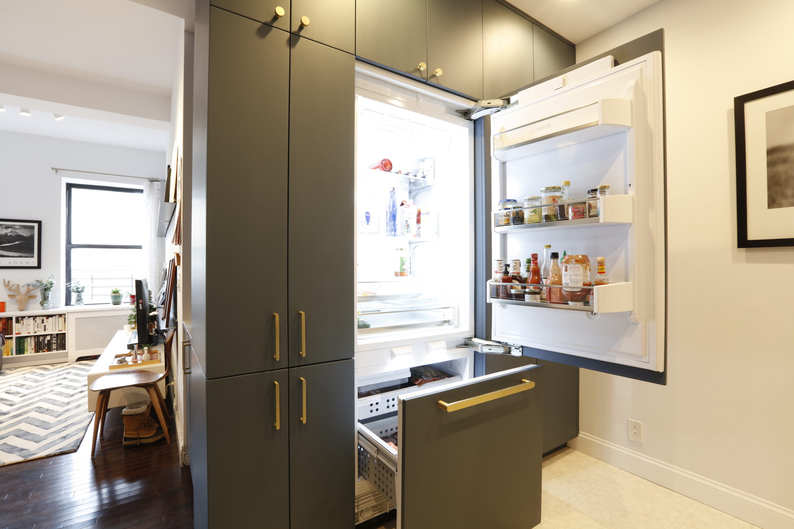 A renovated kitchen featuring gray cabinetry and a hidden fridge cabinet.