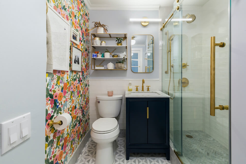 Banheiro com papel de parede e ferragens douradas