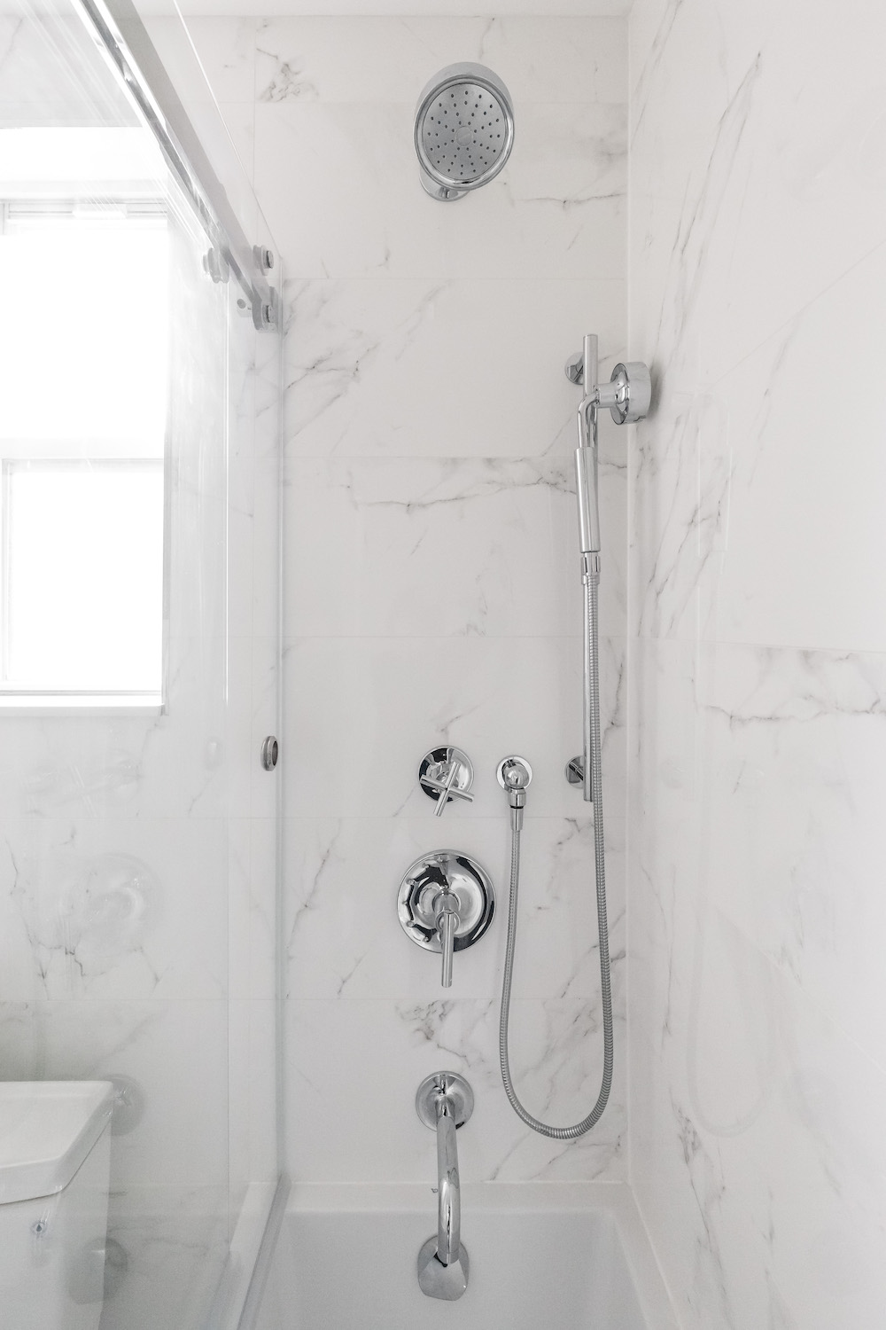 White marble bathtub shower with silver hardware