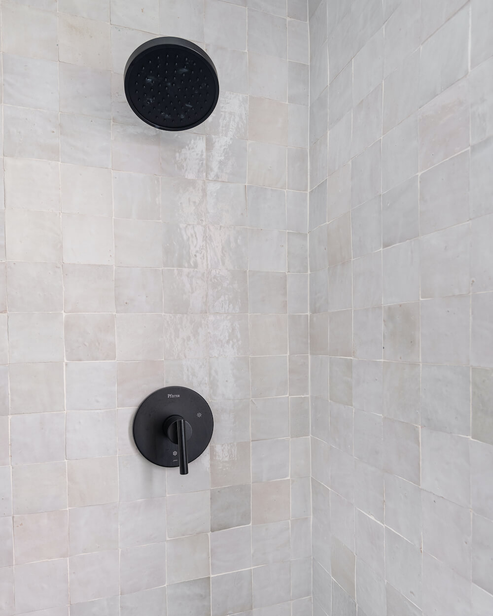 white square bathroom shower tile with black shower fixtures