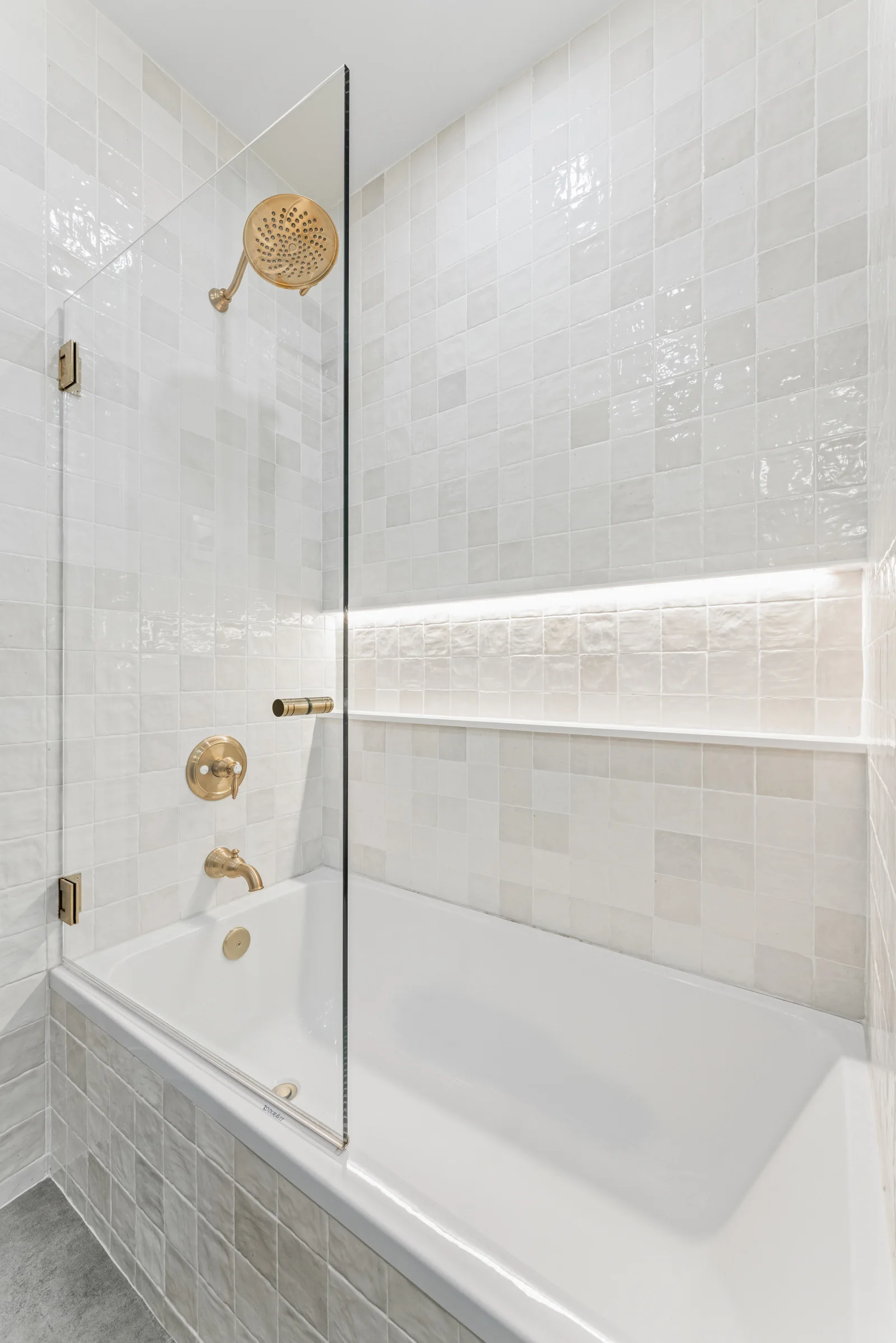 tub shower with glass panel and white textured tile