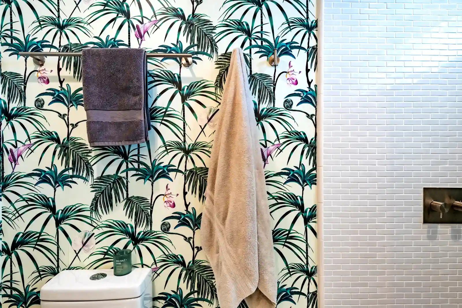 green and white palm wallpaper in bathroom with mini subway shower tile