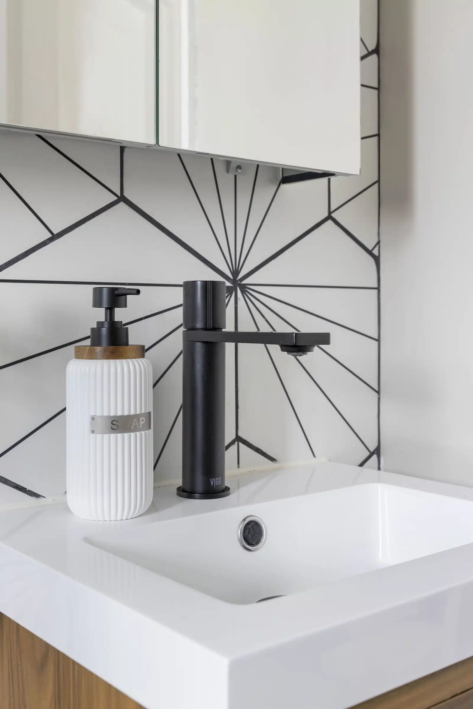 black and white hex patterned bathroom tile with black sink faucet