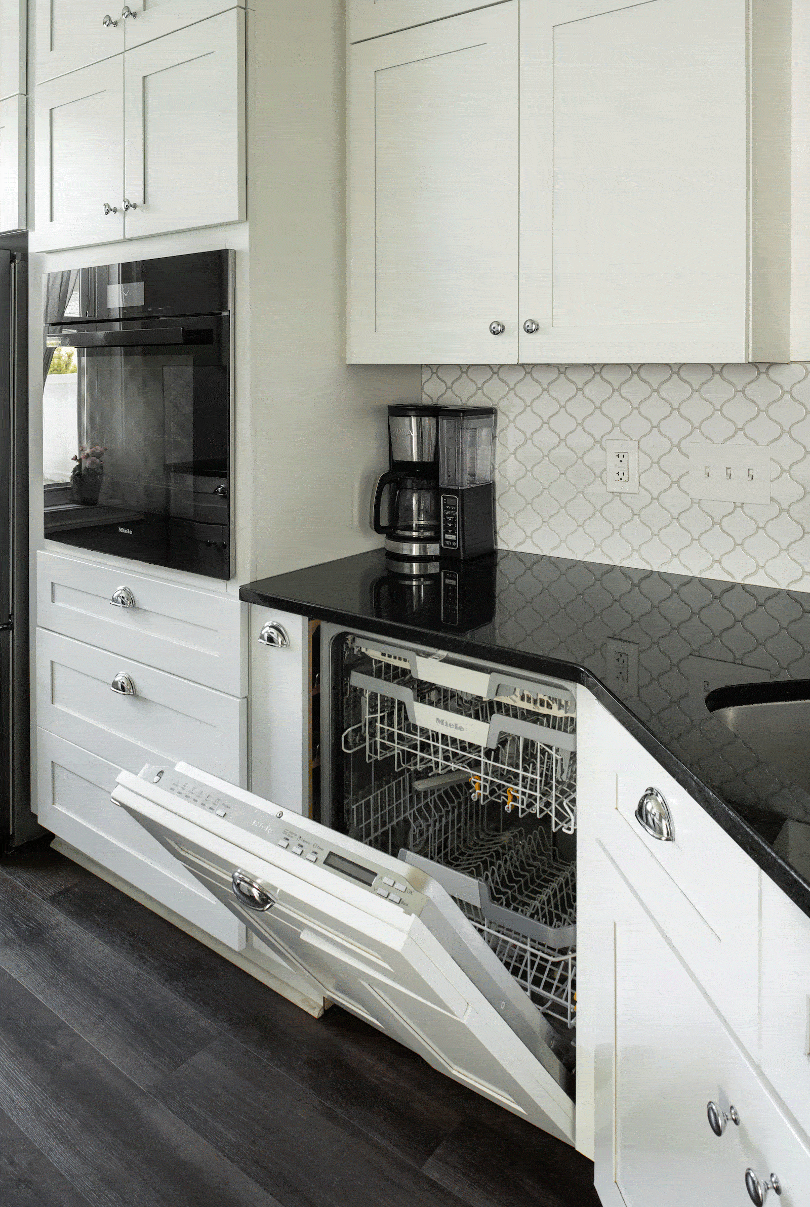 white kitchen with white dishwasher panel and black granite counter
