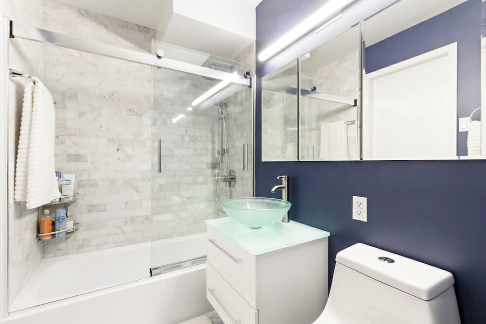 A green glass vessel sink on a white wall-hung vanity