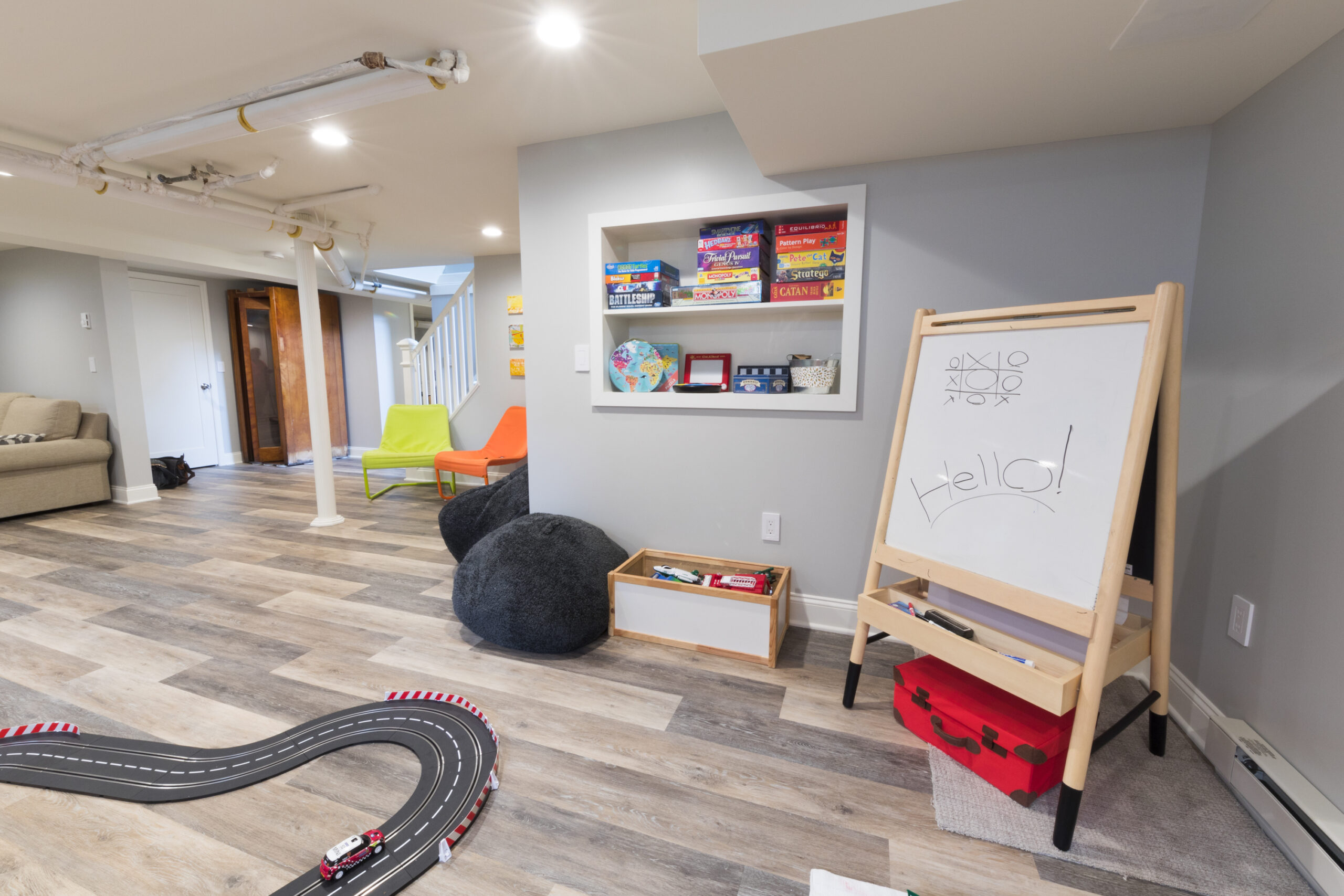 Bergen County basement remodel creates a flexible play area with built-in game storage, an easel, engineered plank flooring, and open family space.