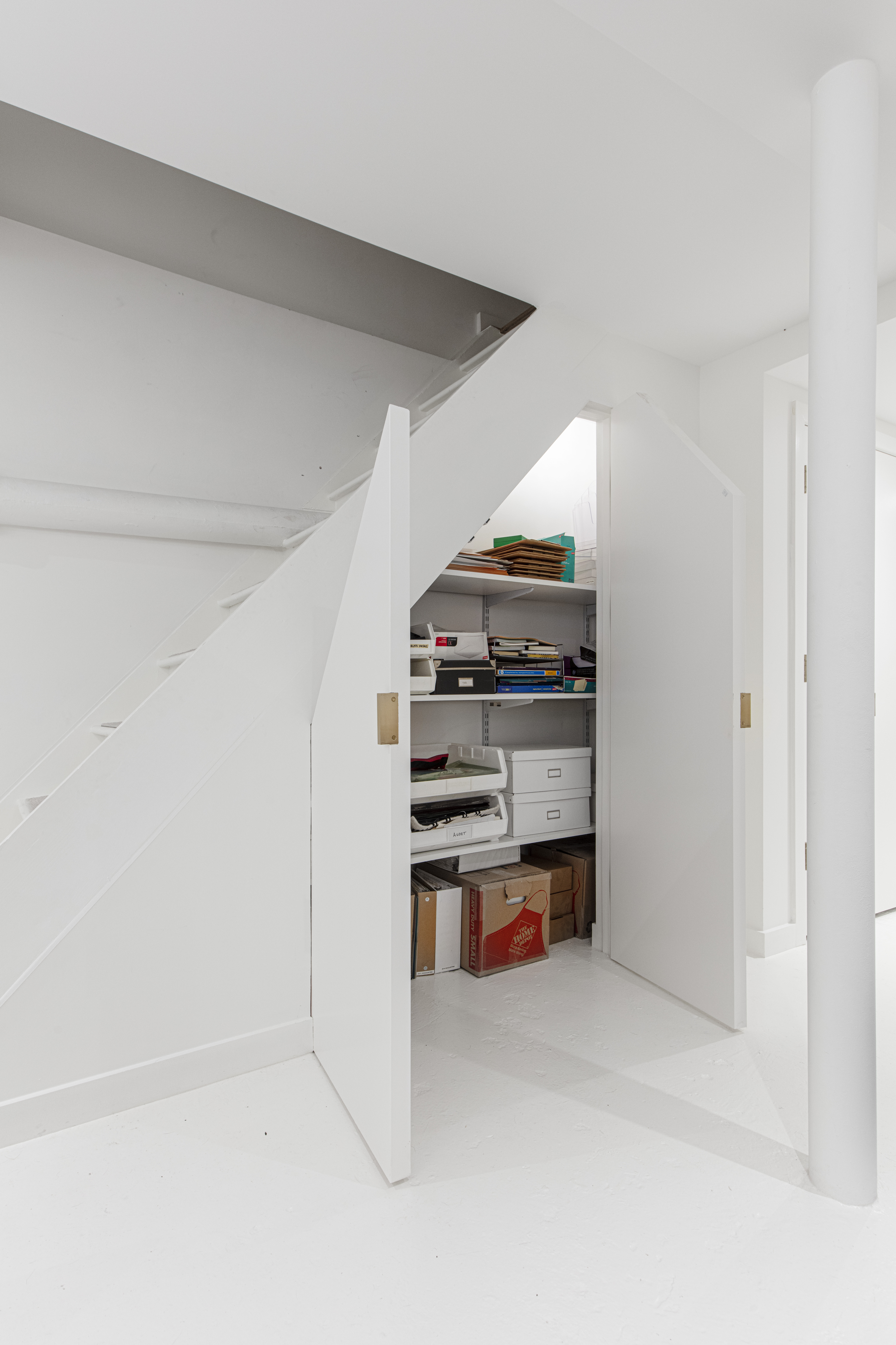 Stuyvesant Heights basement storage uses the space beneath the stairs for built-in closets and shelving, keeping work materials neatly organized.