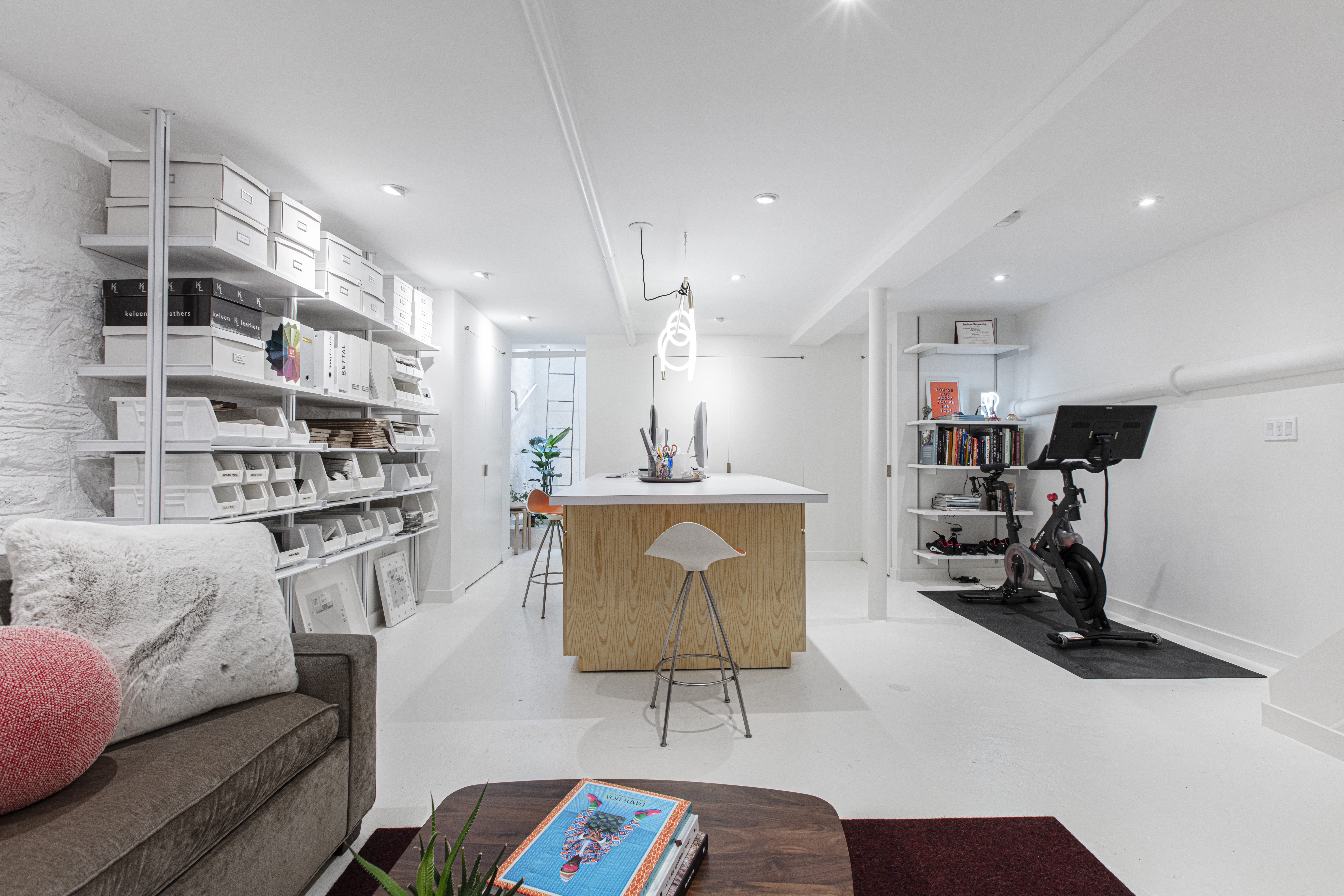 Brooklyn basement remodel with a central work island, open shelving, lounge seating, recessed lighting, and a dedicated exercise area beside the office.