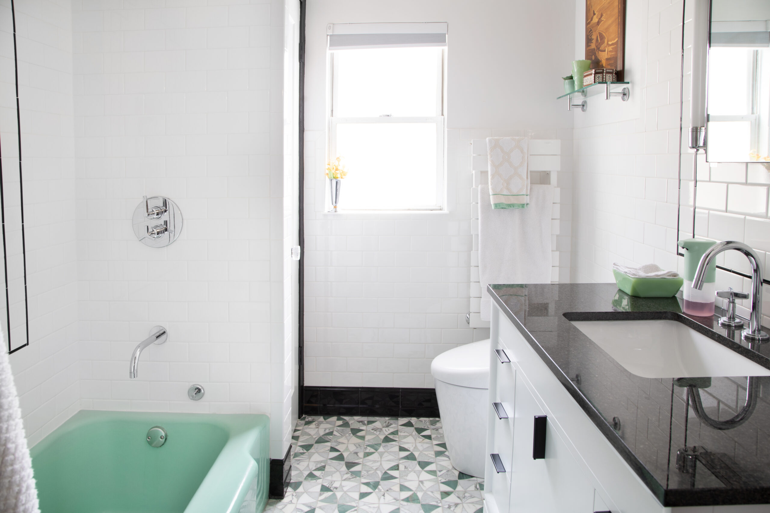 Jersey City bathroom remodel with mint green bathtub, white subway tile, patterned stone floor, and a new vanity with black top.
