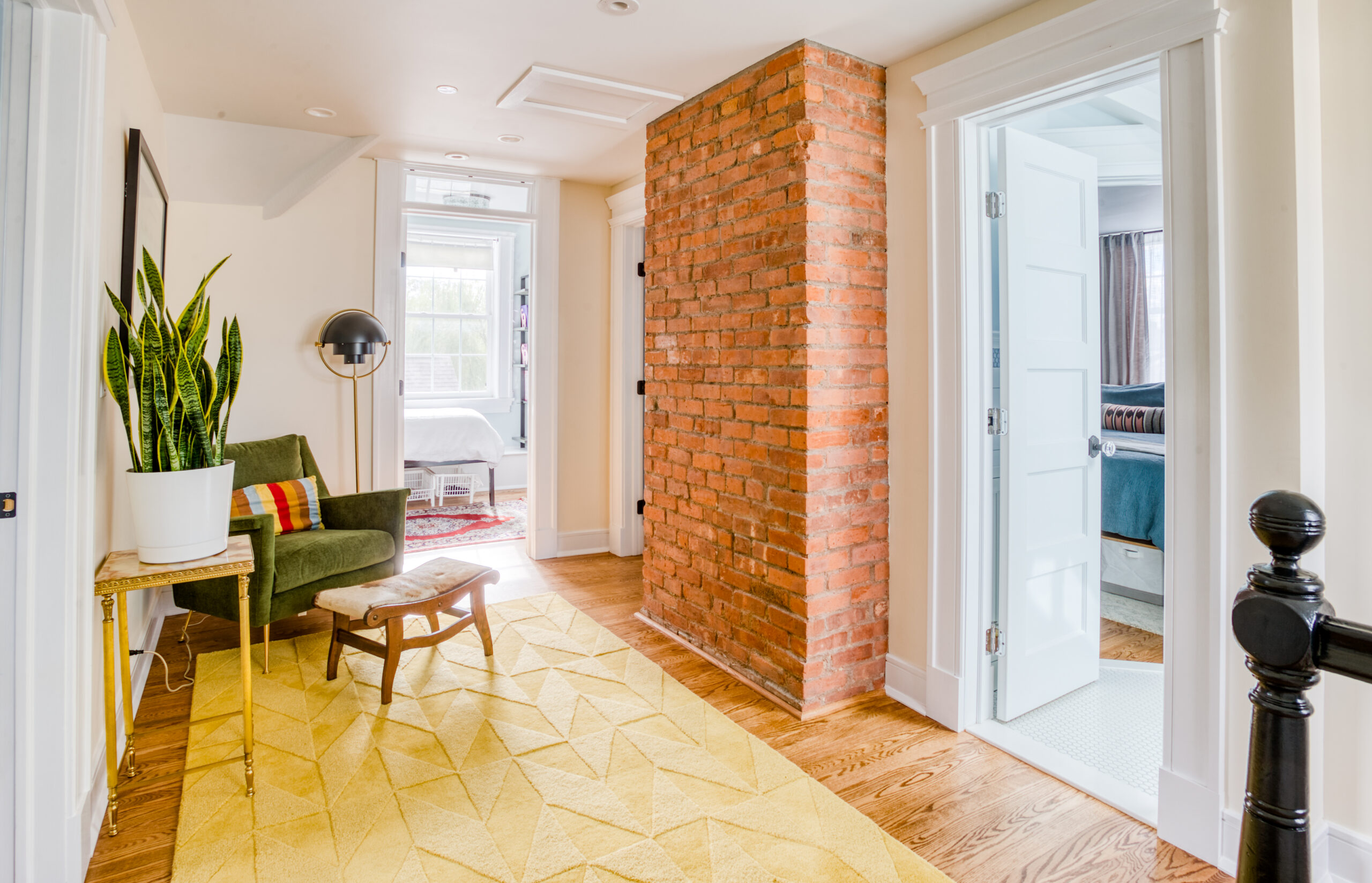 Finished third-floor landing with exposed brick chimney, new doorways, and bright windows, showing space gains from a Westchester attic remodel.
