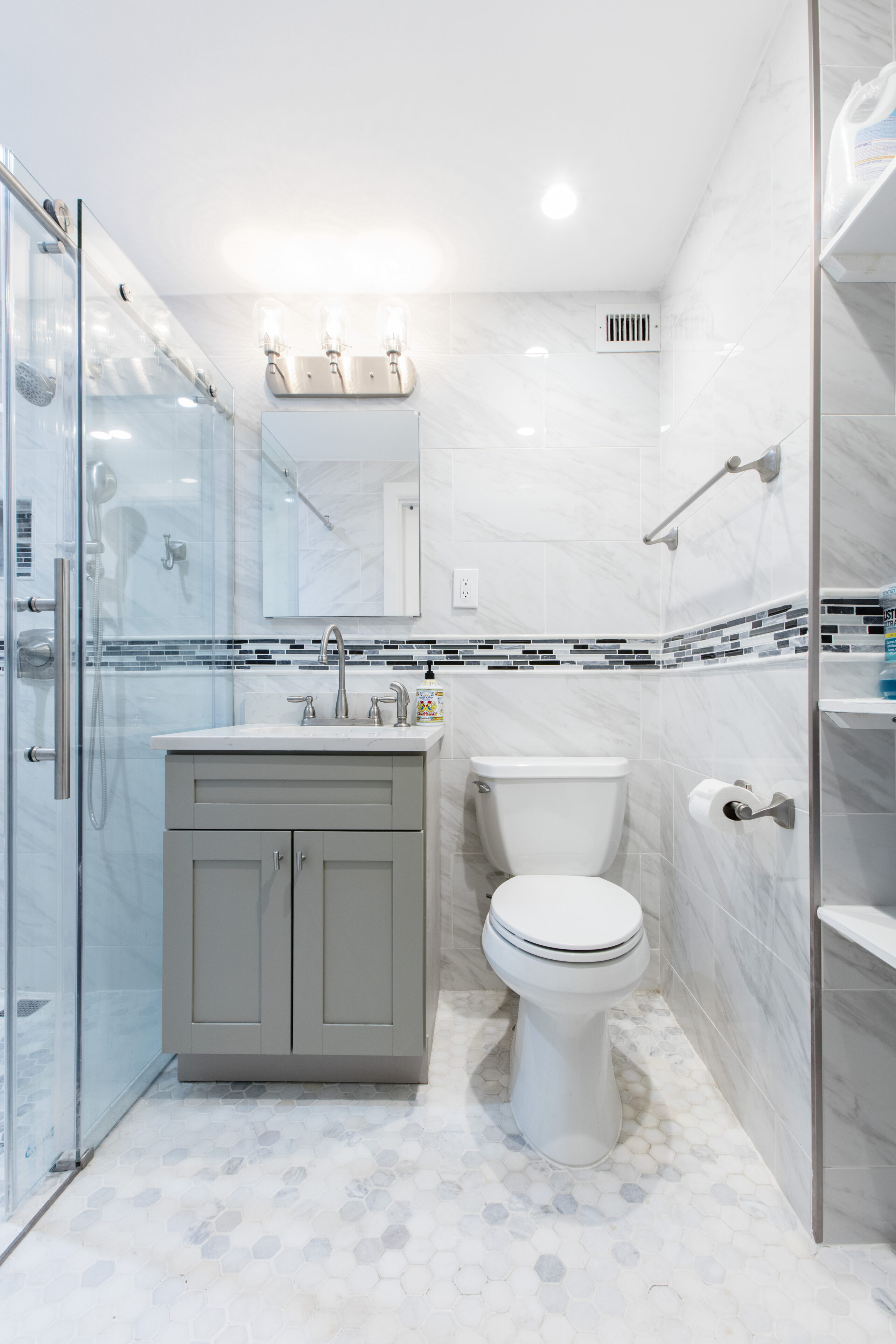 Bright bath with glass shower, vanity and toilet, grab bars and clear floor space for a senior-friendly bathroom design built for safety.