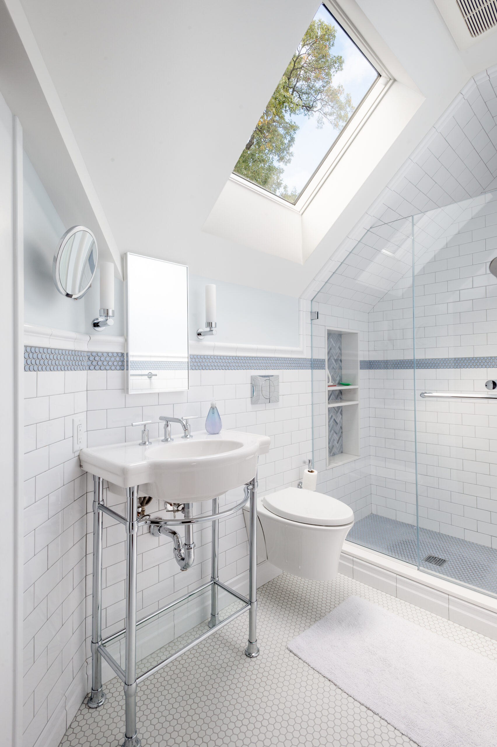 New attic bathroom with skylight, subway walls, hex tile floor, glass shower, and fixtures, a smart fit for sloped-ceiling remodels.