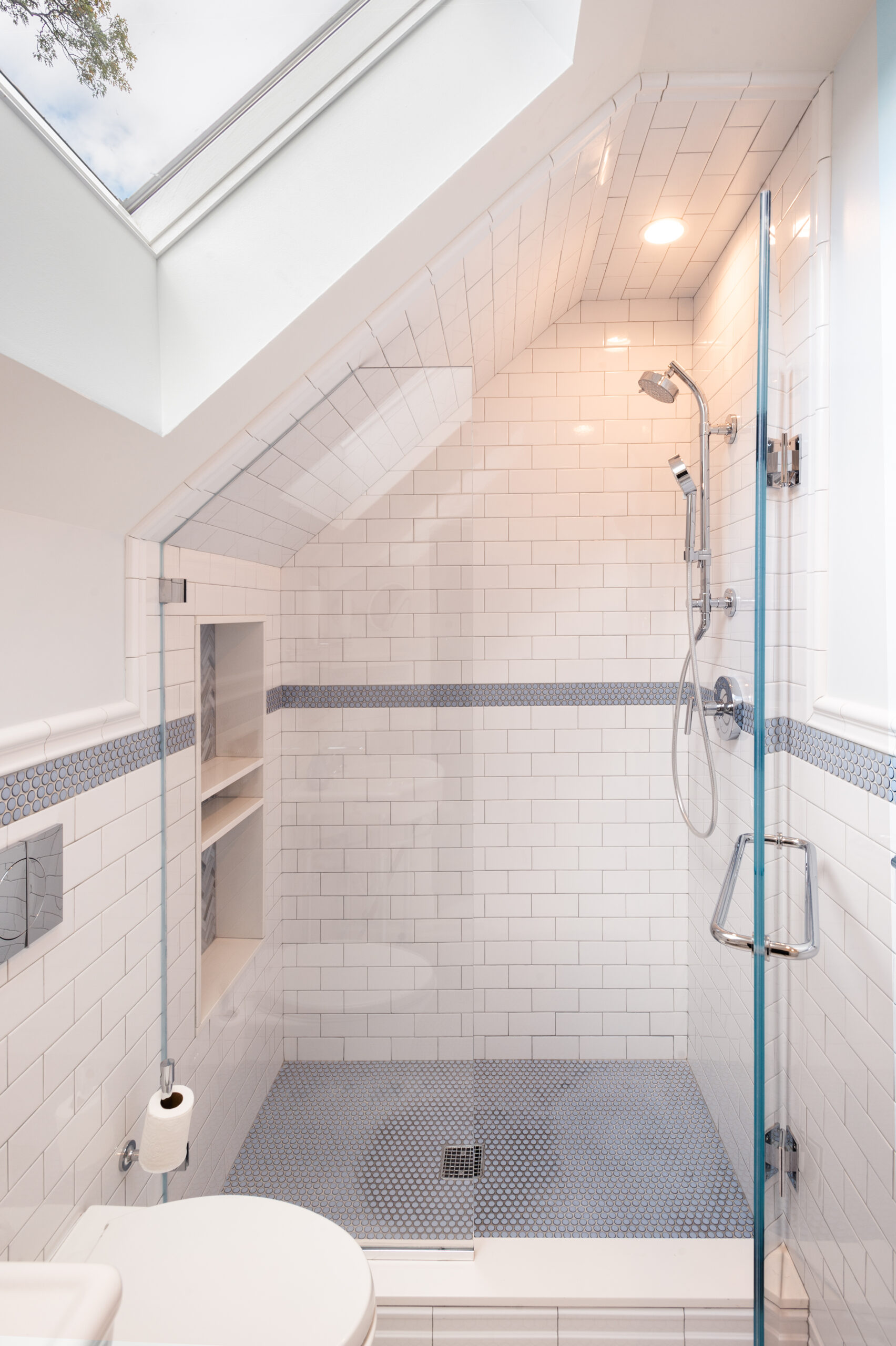 Renovated Westchester bathroom with skylight, chrome fixtures, walk-in shower, and white subway tile.