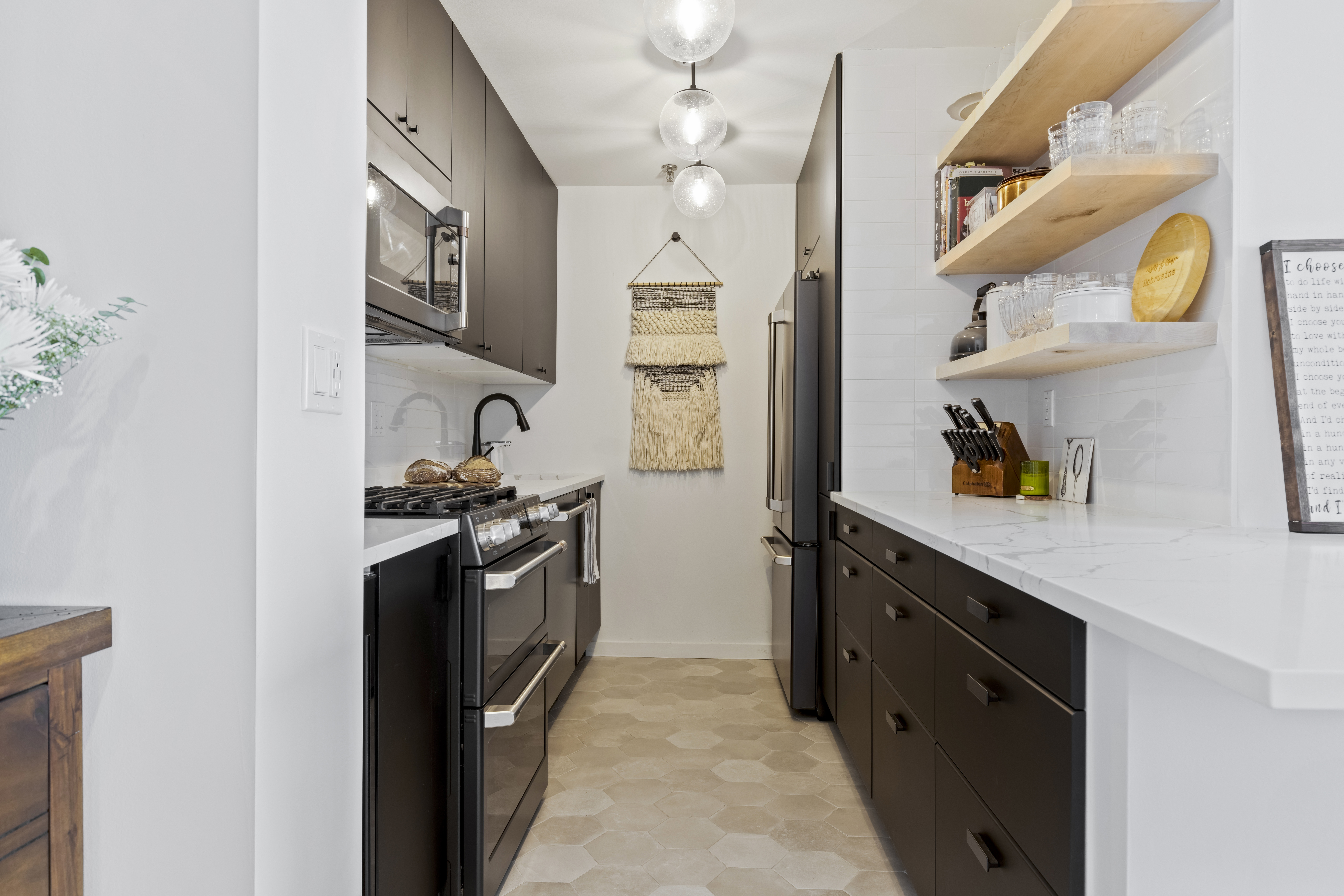 A galley kitchen with dark brown cabinets, open shelving, and hex tile floors creates a clean and modern layout.
