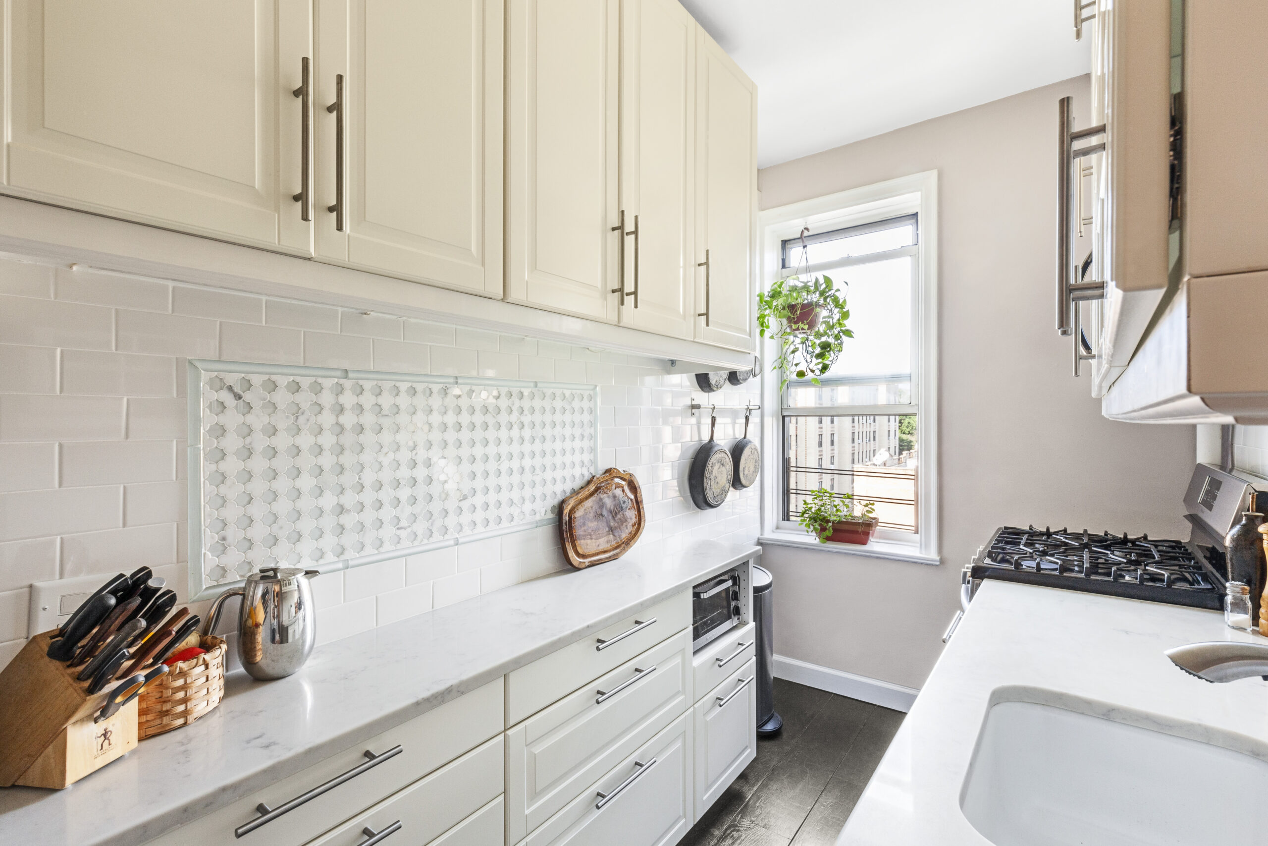 Cream cabinets, white tile, and marble counters give this galley kitchen a bright, polished, and timeless feel.