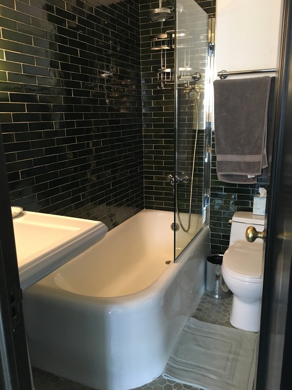 Before a tub to shower remodel showcasing a white tub and toilet with glass partition.