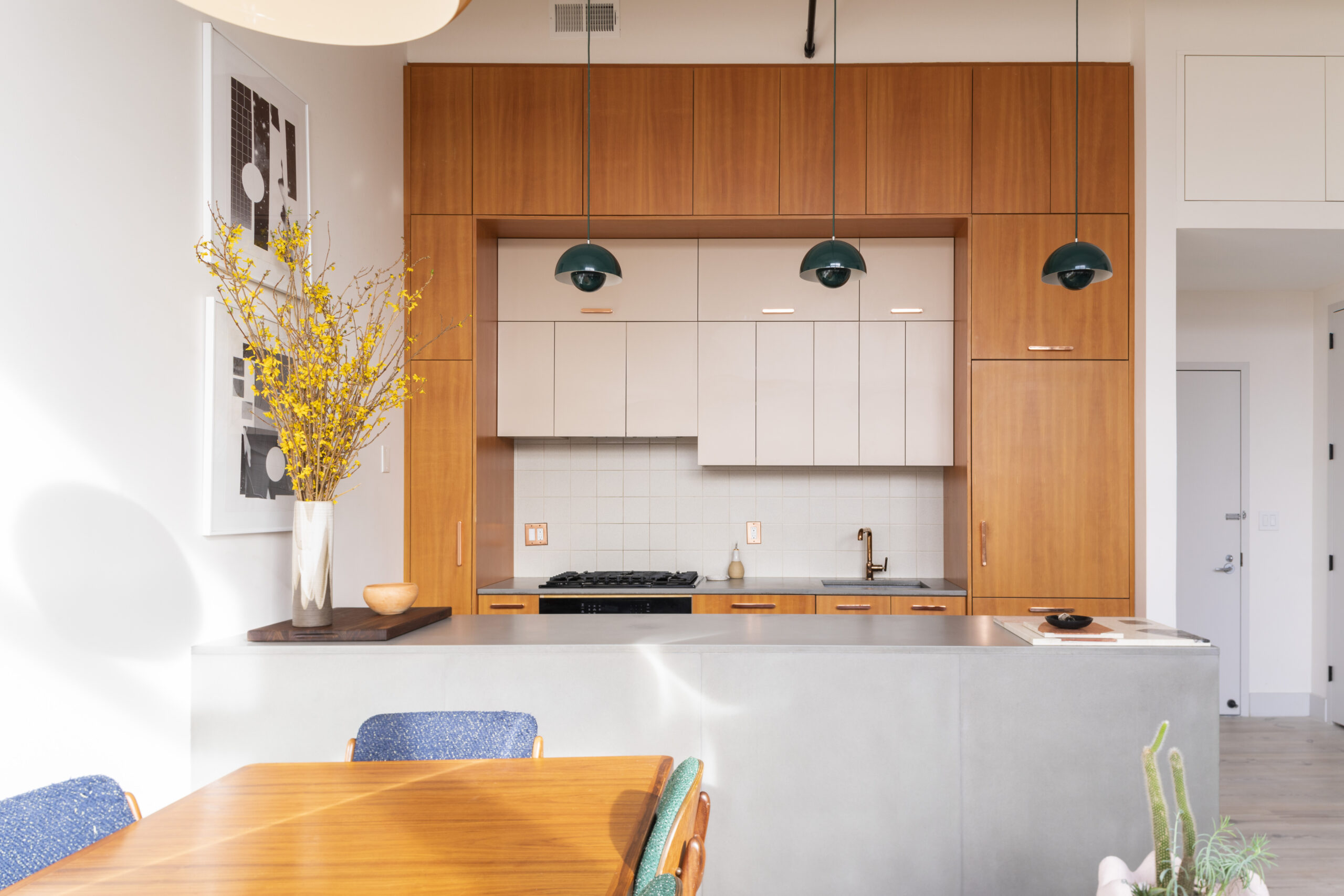 Warm wood cabinets, soft taupe uppers, and clean tile details shape a modern kitchen with mid century influence.
