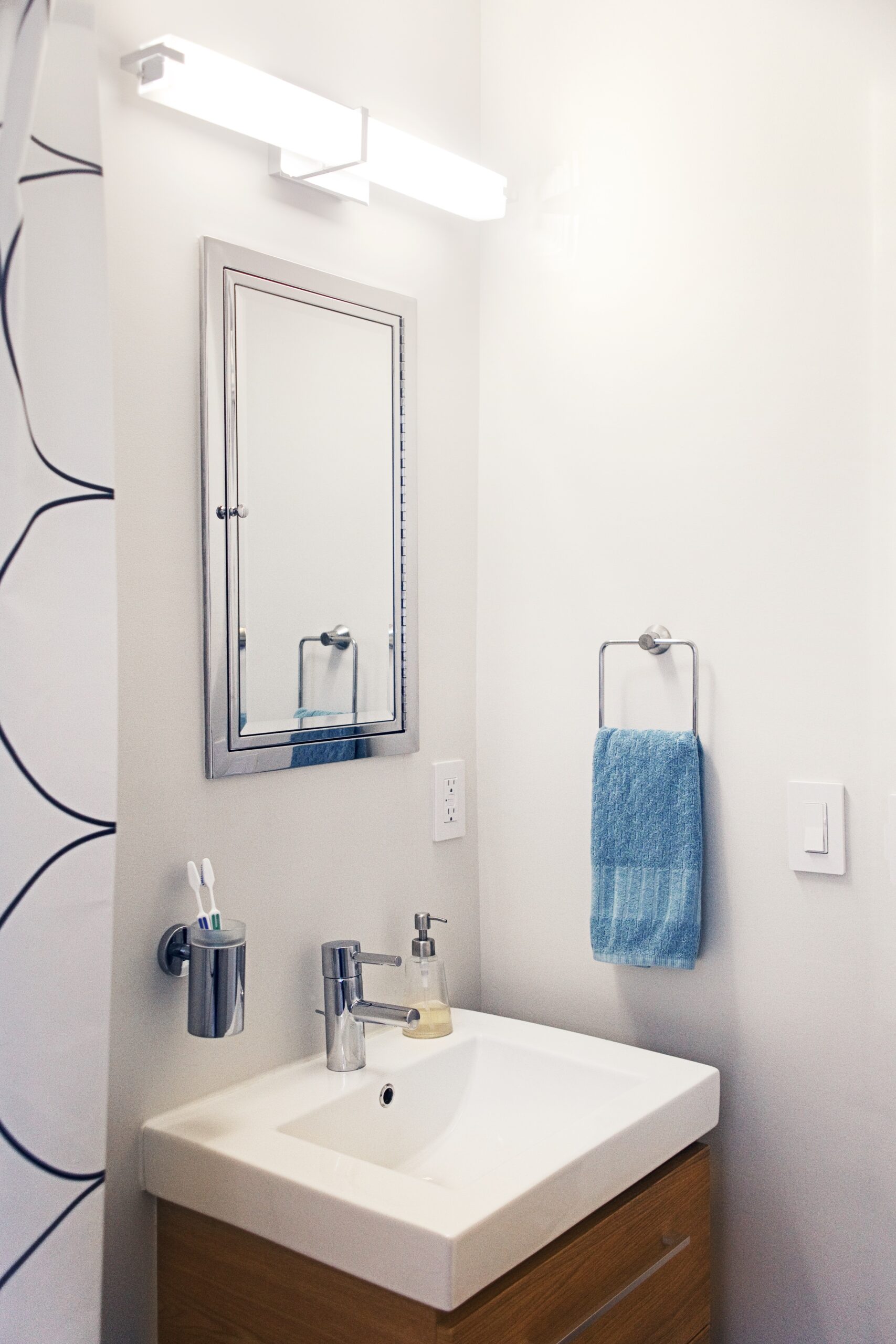 Modern vanity with white sink, chrome faucet, and blue towel in renovated Murray Hill bathroom.