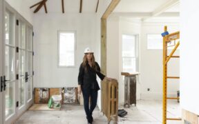 Woman wearing a hard hat standing in an interior of a home being remodeled.