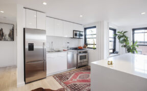 Bright white kitchen with long counter run and large island; plan fits holiday hosting, with prep space and a clear gathering spot for guests.