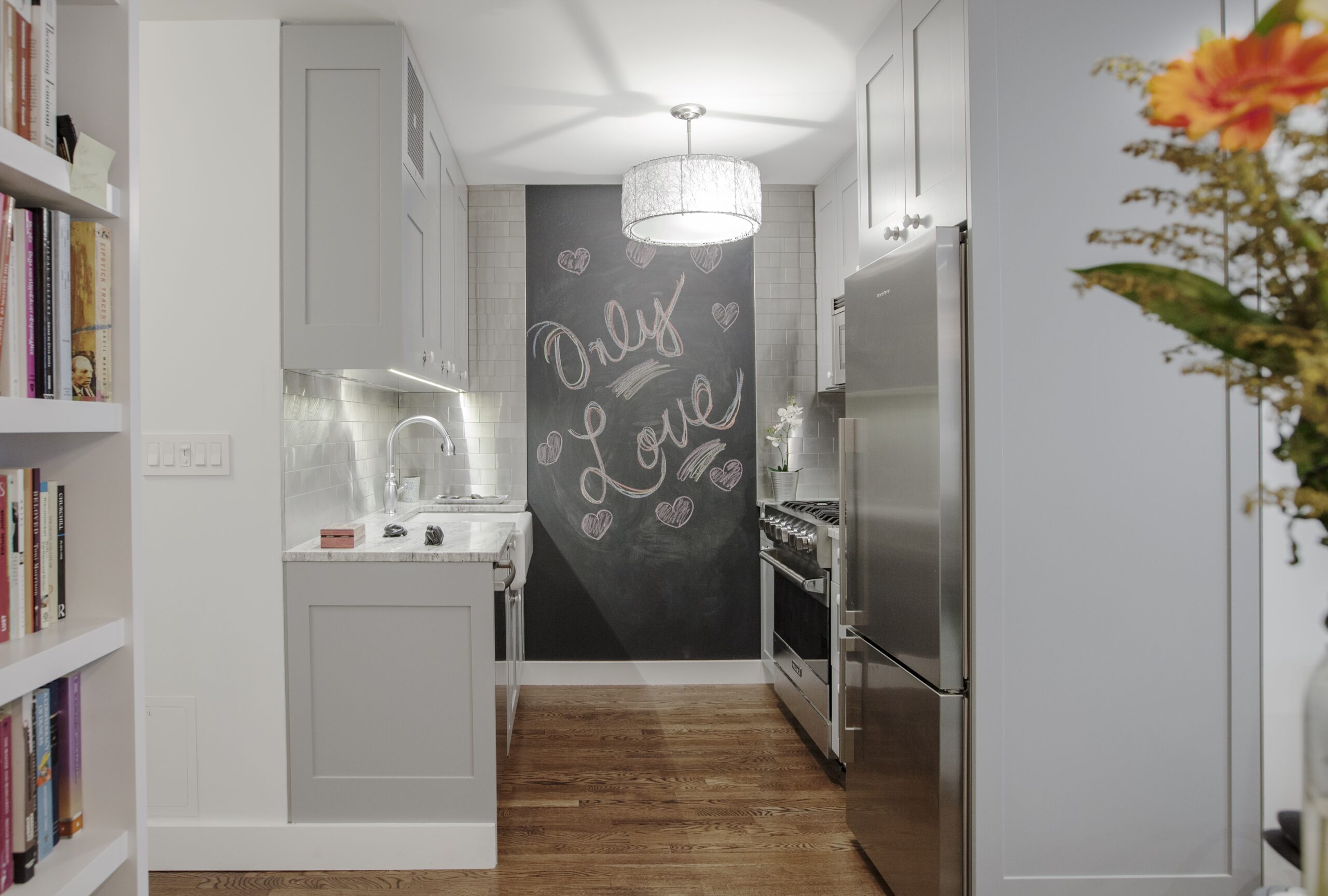 A sleek kitchen with stainless steel tiles behind the stove and sink, bright lighting, and gray cabinetry offering a modern and inviting atmosphere.