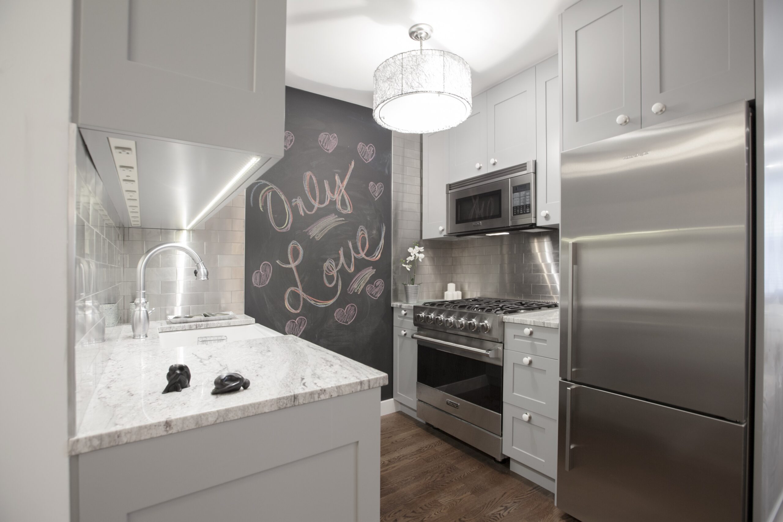 Renovated kitchen with a stylish stainless steel backsplash, a farmhouse sink, and modern appliances. Clean and contemporary with ample counter space.