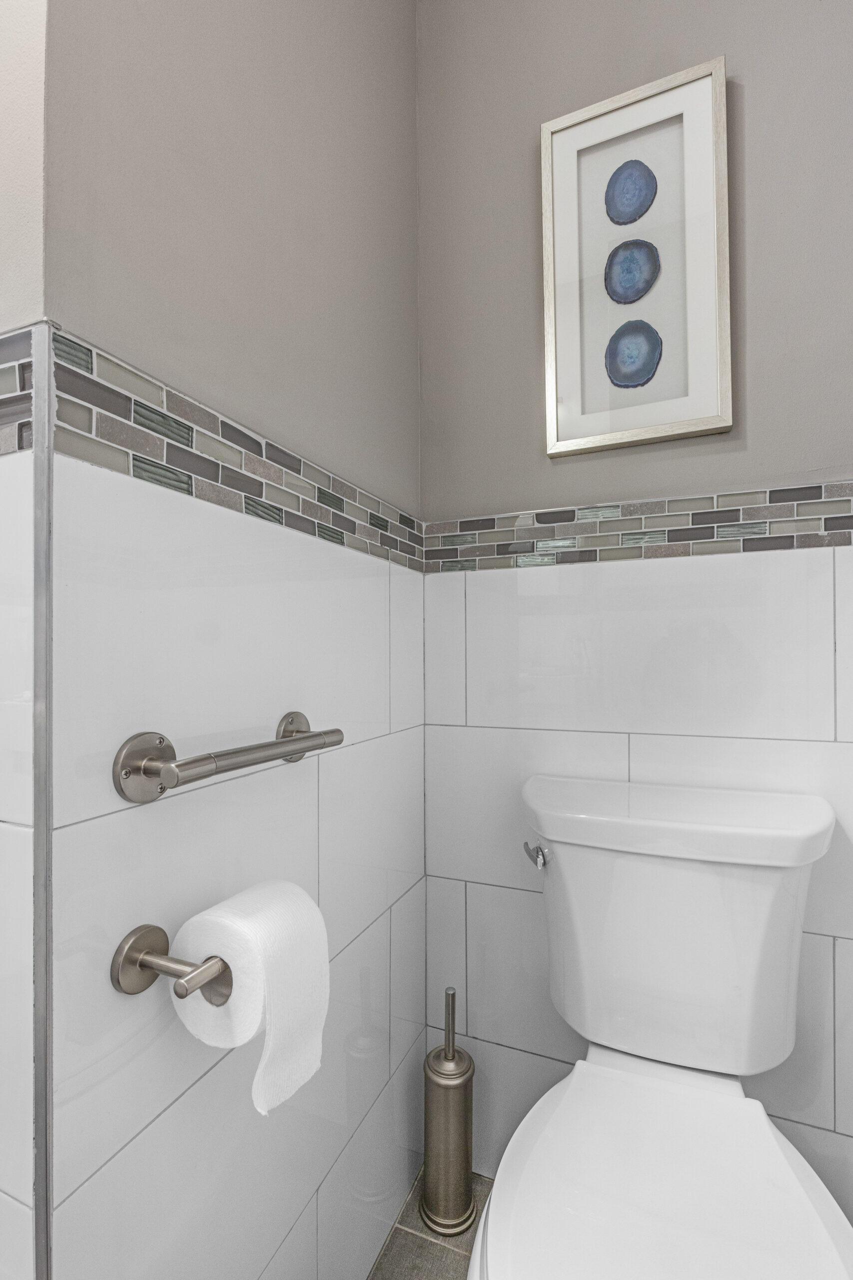 Toilet corner with sturdy horizontal grab bar and reachable tissue holder, giving seniors safer support for standing and sitting in the bathroom.