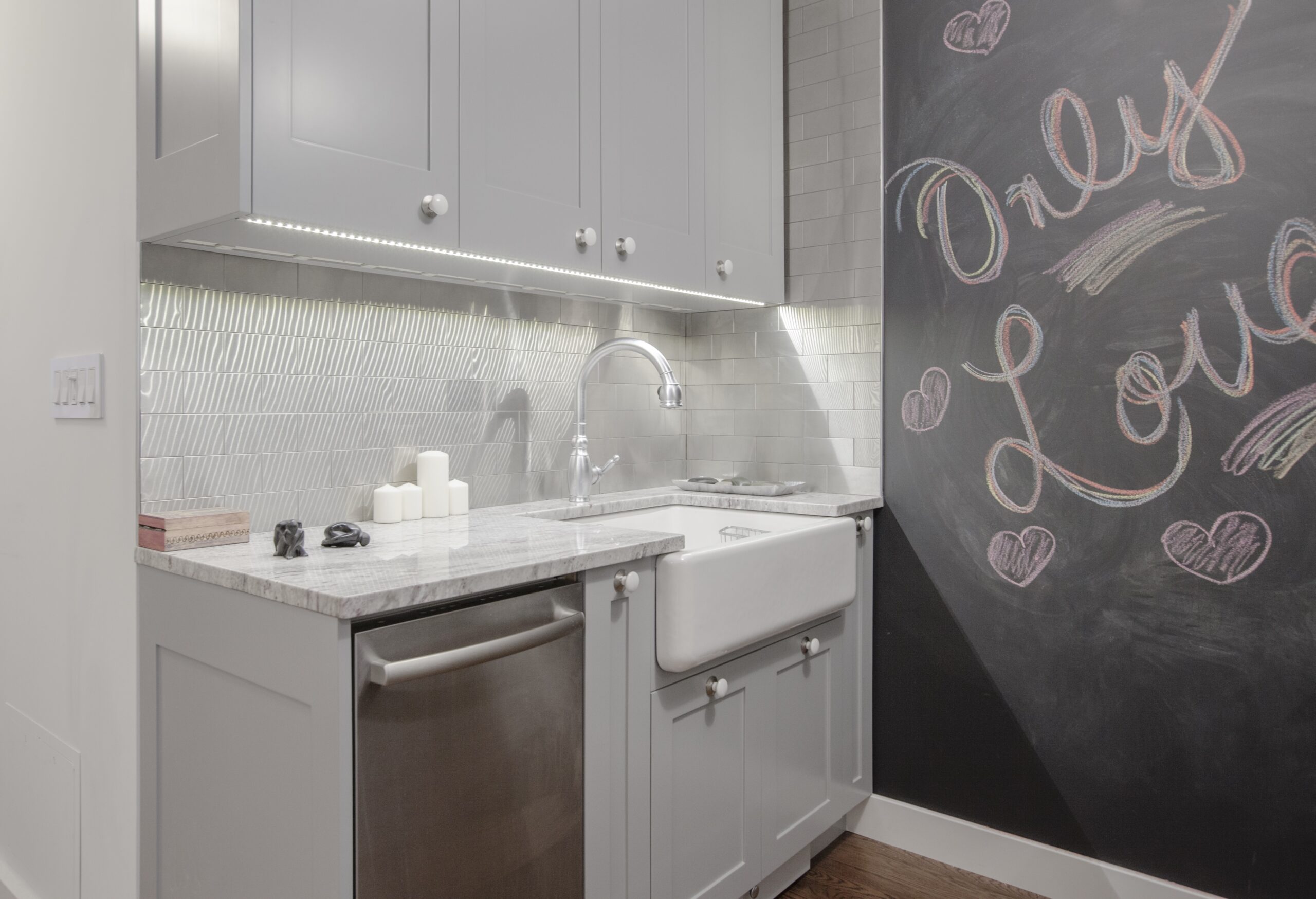 Contemporary kitchen featuring stainless steel tile backsplash, a spacious sink area, and modern lighting. Subtle textures and sleek finishes throughout.