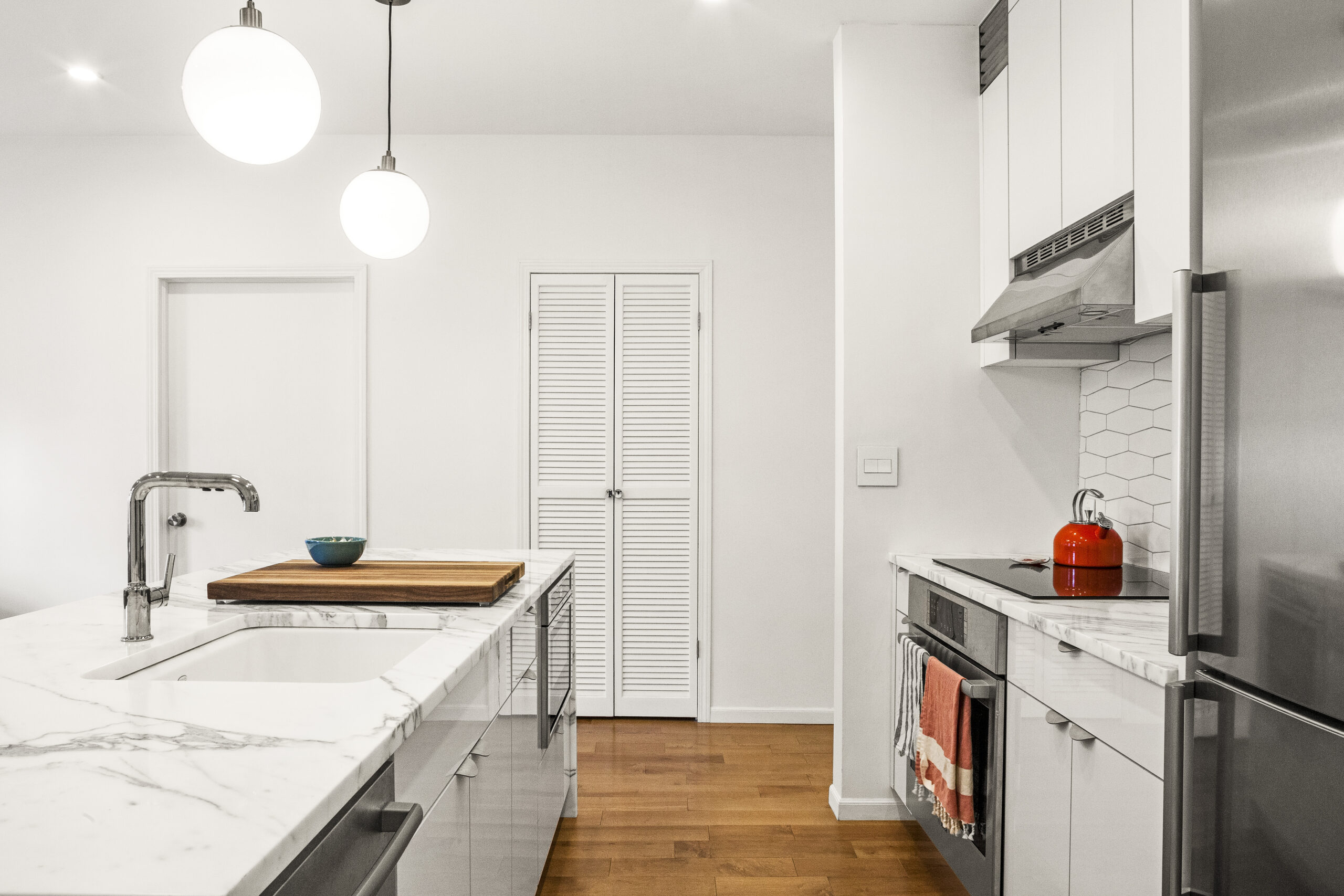 White kitchen with marble island and hex tile backsplash; wide surfaces suit holiday entertaining, with easy circulation for guests and servers.
