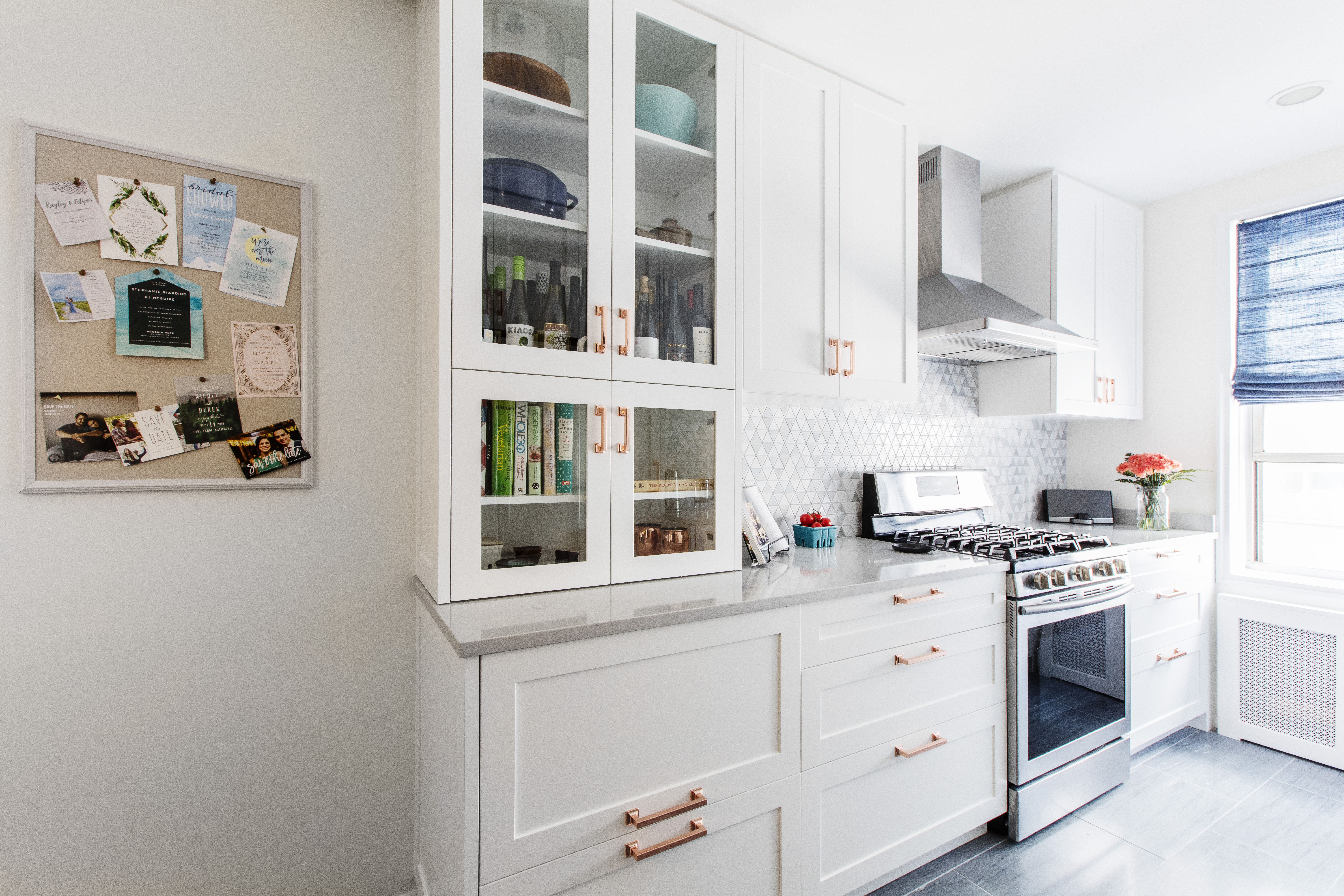 Kitchen with glass cabinets, range with hood, and cork post-it board