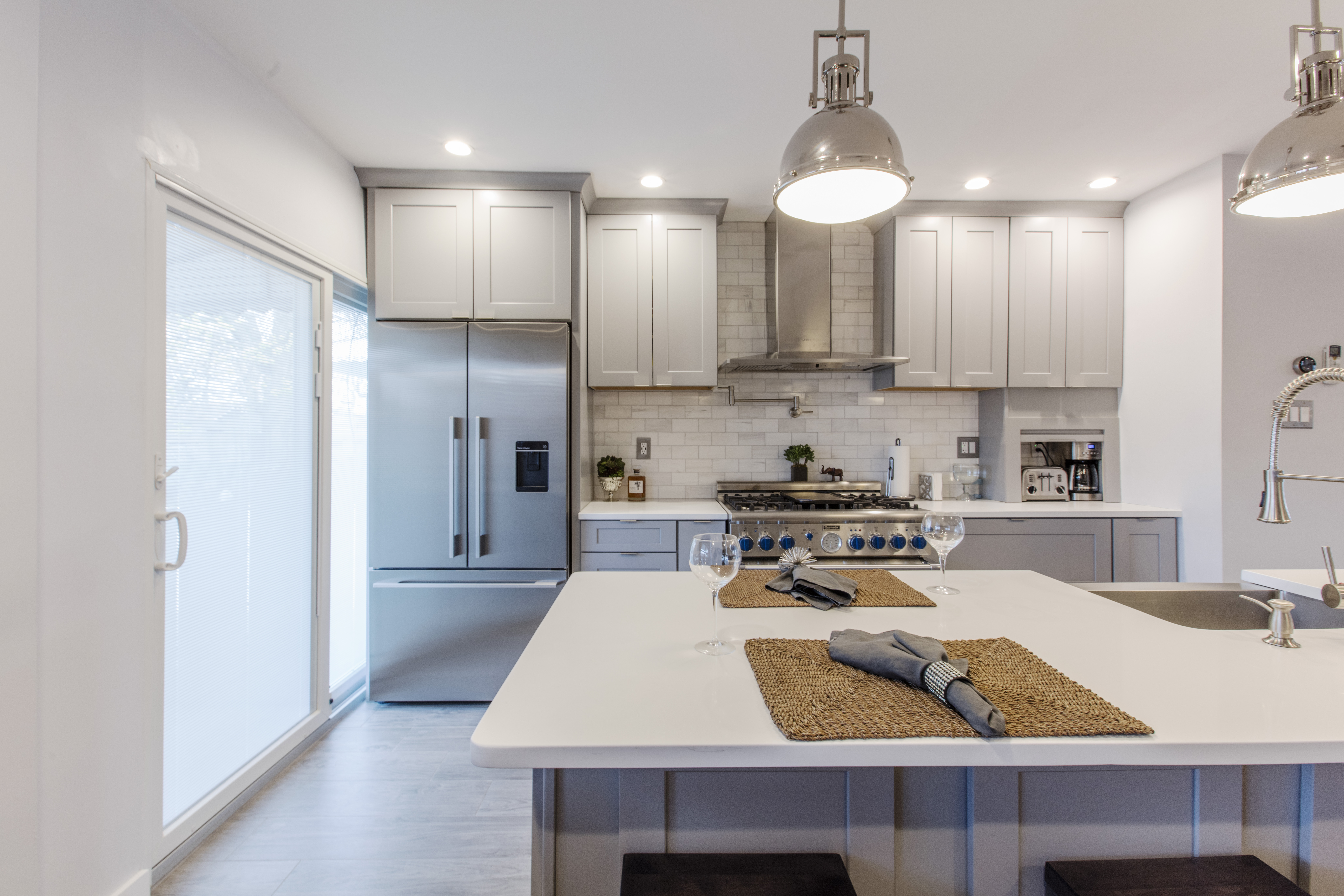 Kitchen with gray Shaker cabinets, quartz kitchen island, and warm lighting
