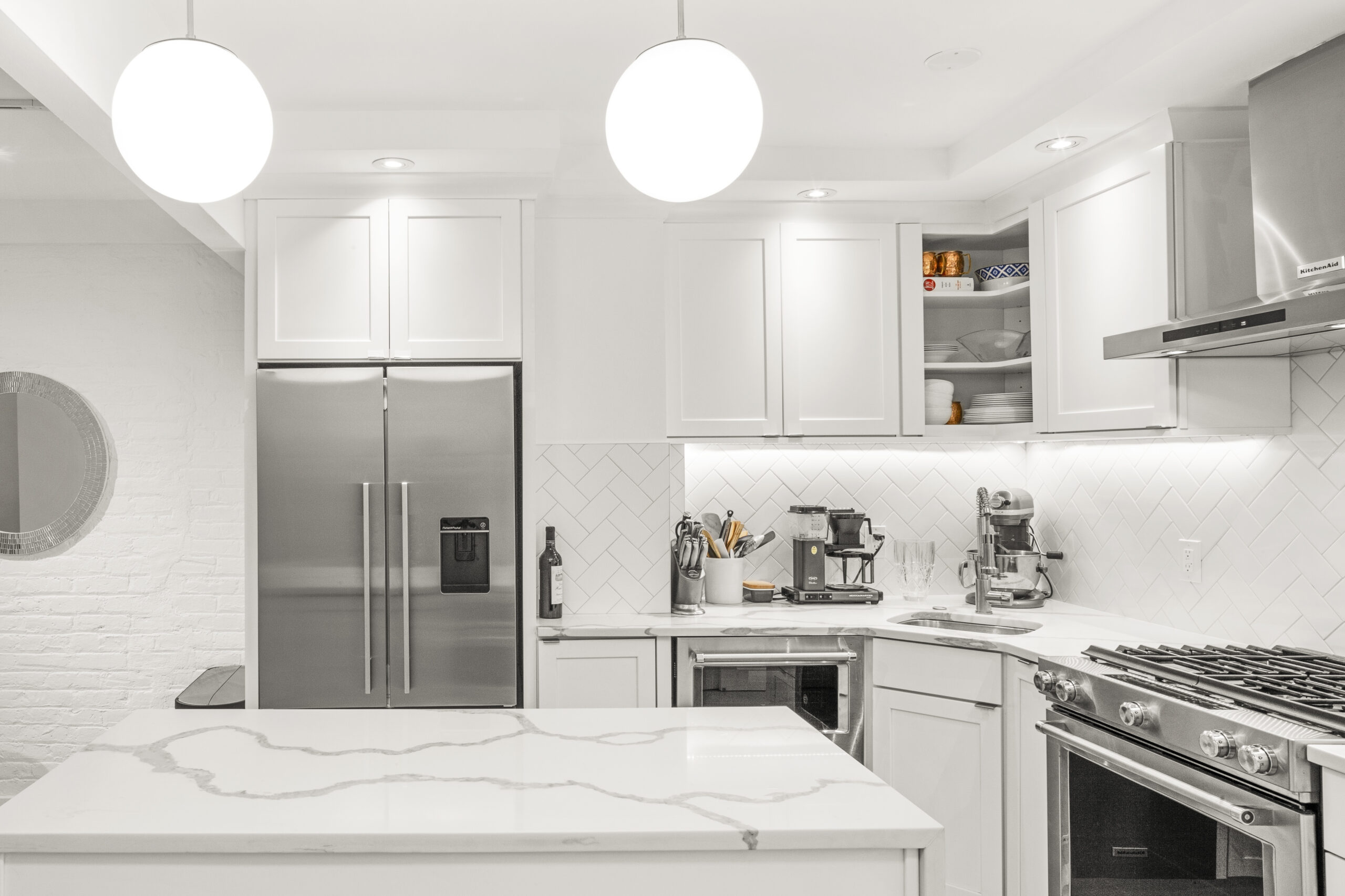 White Shaker cabinets, quartz kitchen island, and bright lighting