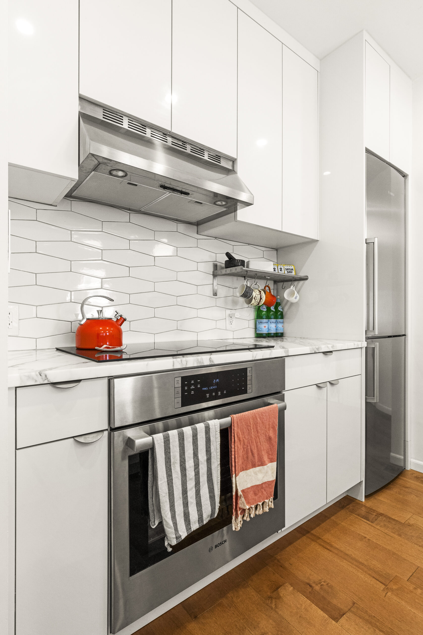 White kitchen cabinets, hex backsplash, and wooden flooring