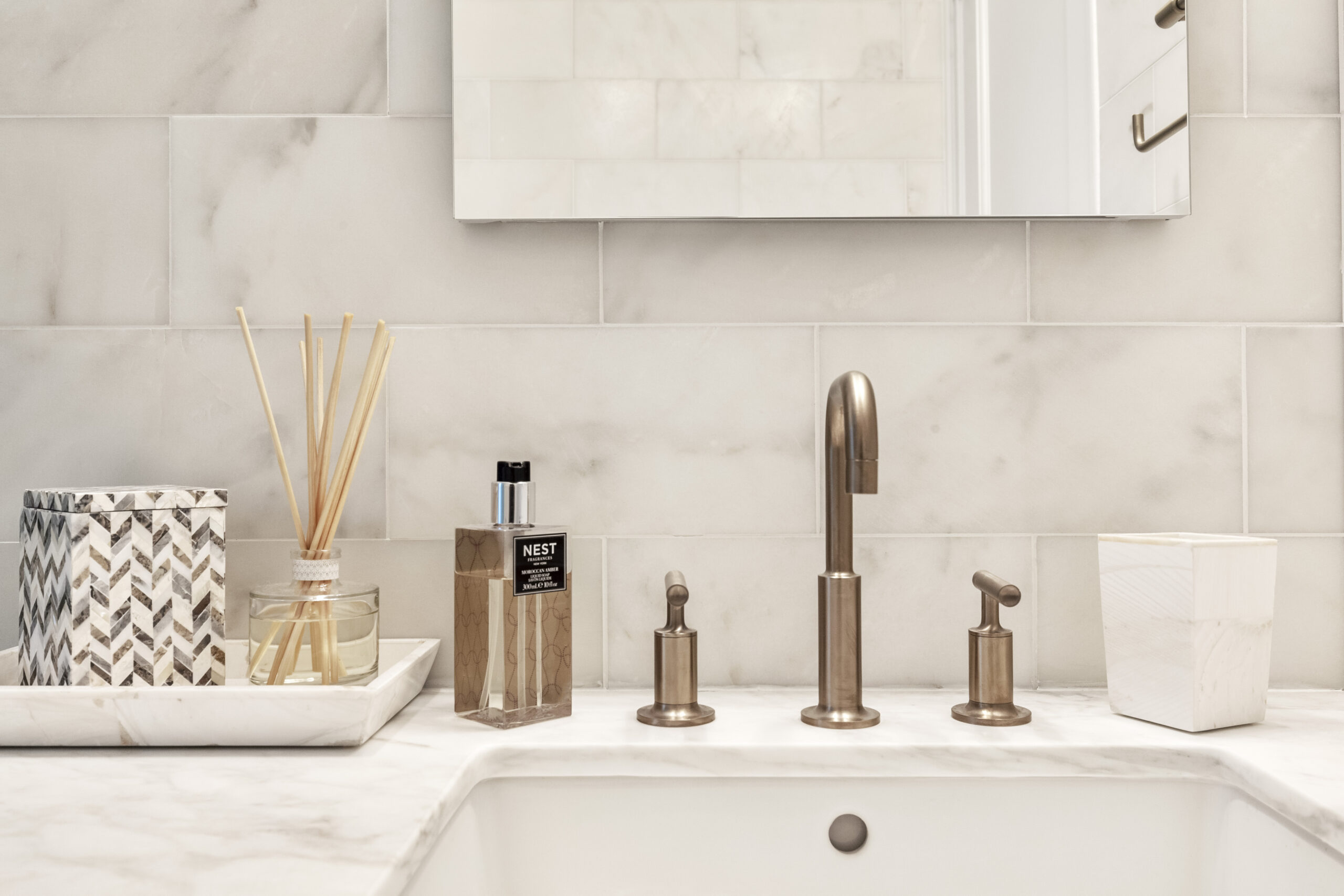 Calacatta marble subway wall tile with brass fixtures on Calacatta marble vanity counter