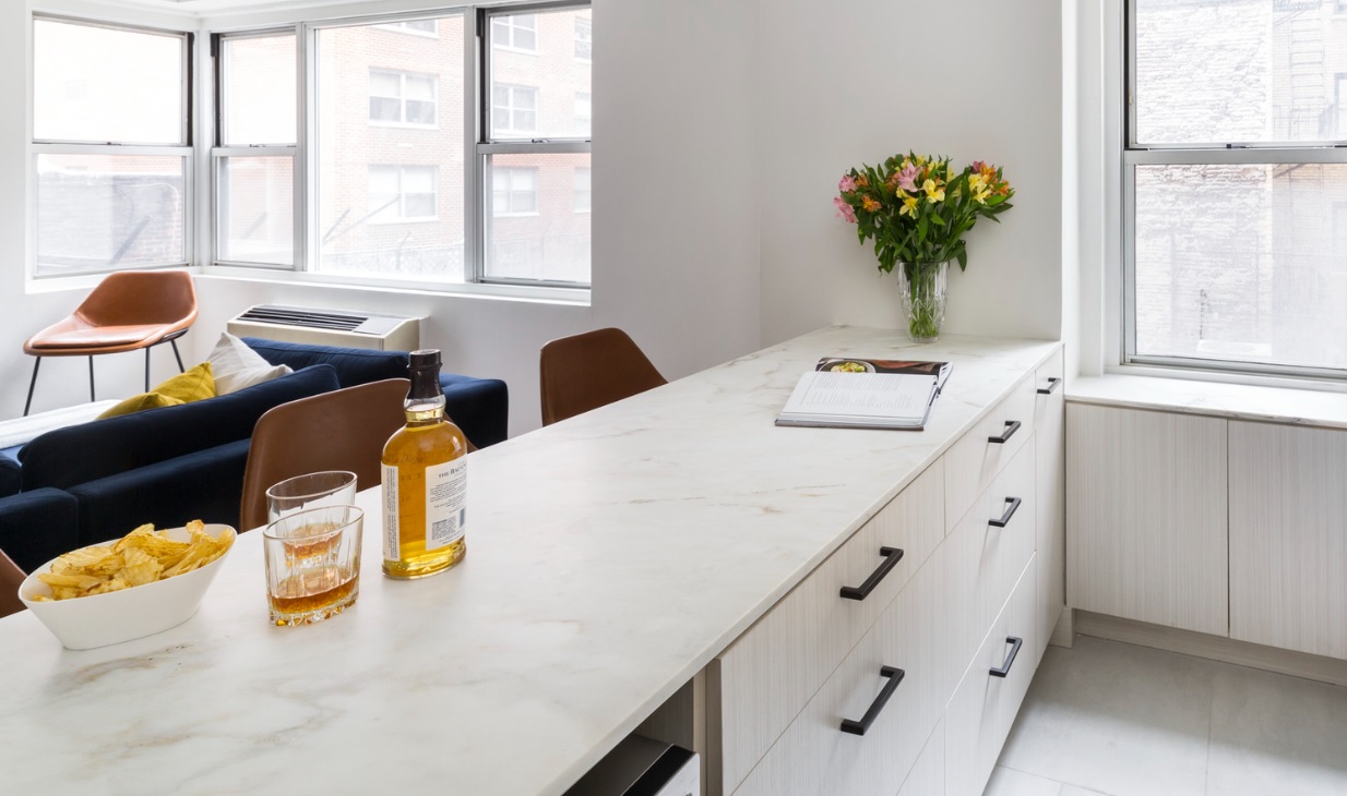 Calacatta marble kitchen peninsula with liquor and a bouquet of flowers on top