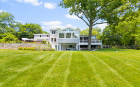 Backyard view of a home addition with tall windows, rear deck access, and a wide lawn. It fits content about new square footage and higher rebuild value.