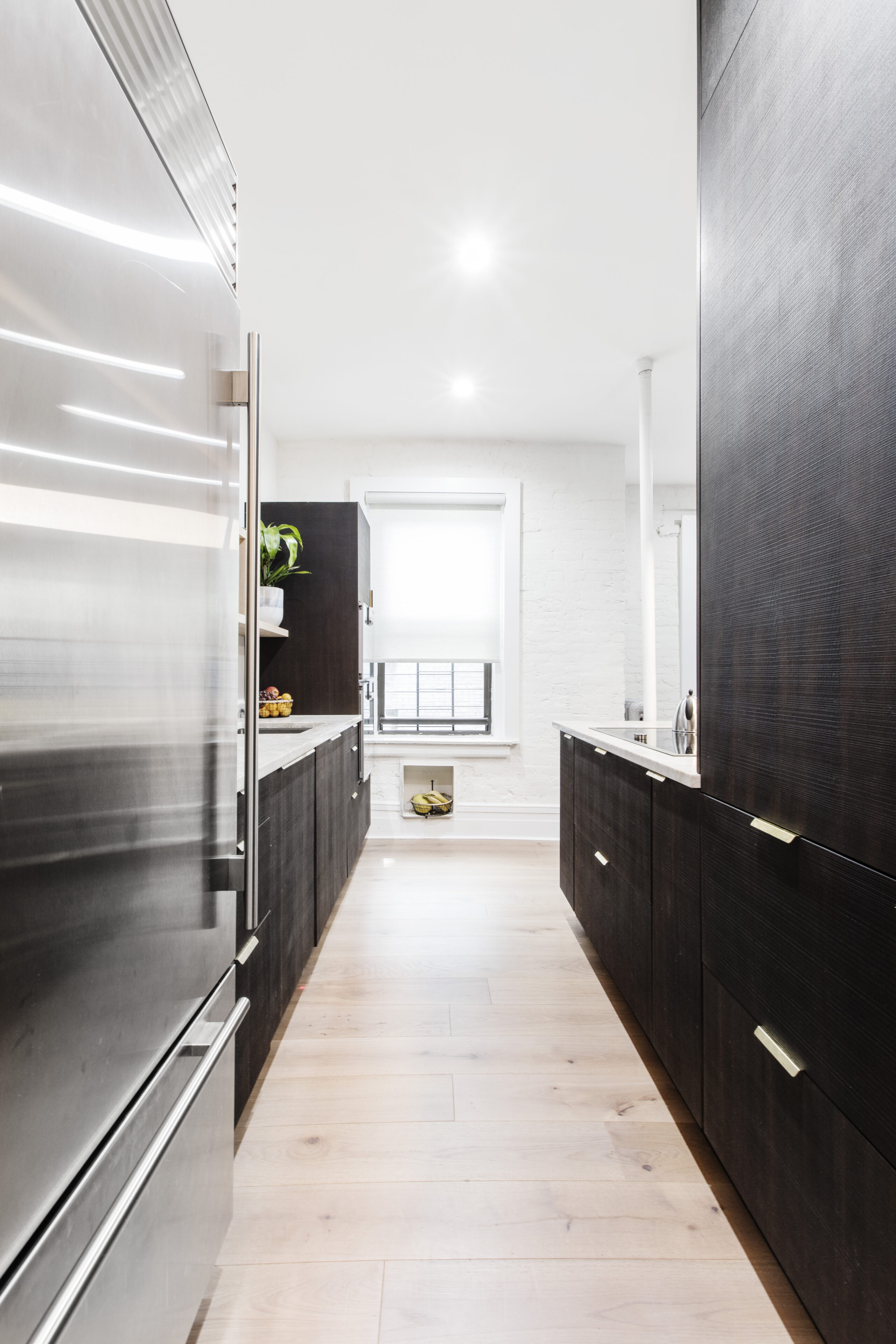 A Manhattan tin ceiling kitchen with dark wood cabinetry, light wood flooring, and an open window