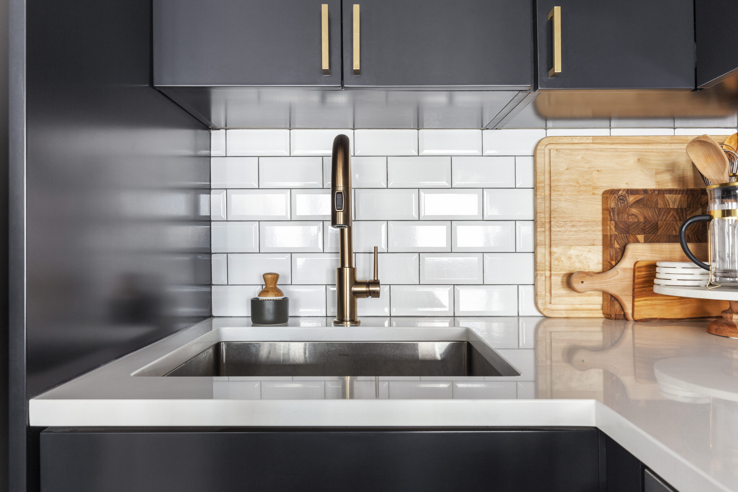 White subway tile backsplash, brass faucet, and white quartz countertop in a renovated studio loft kitchen